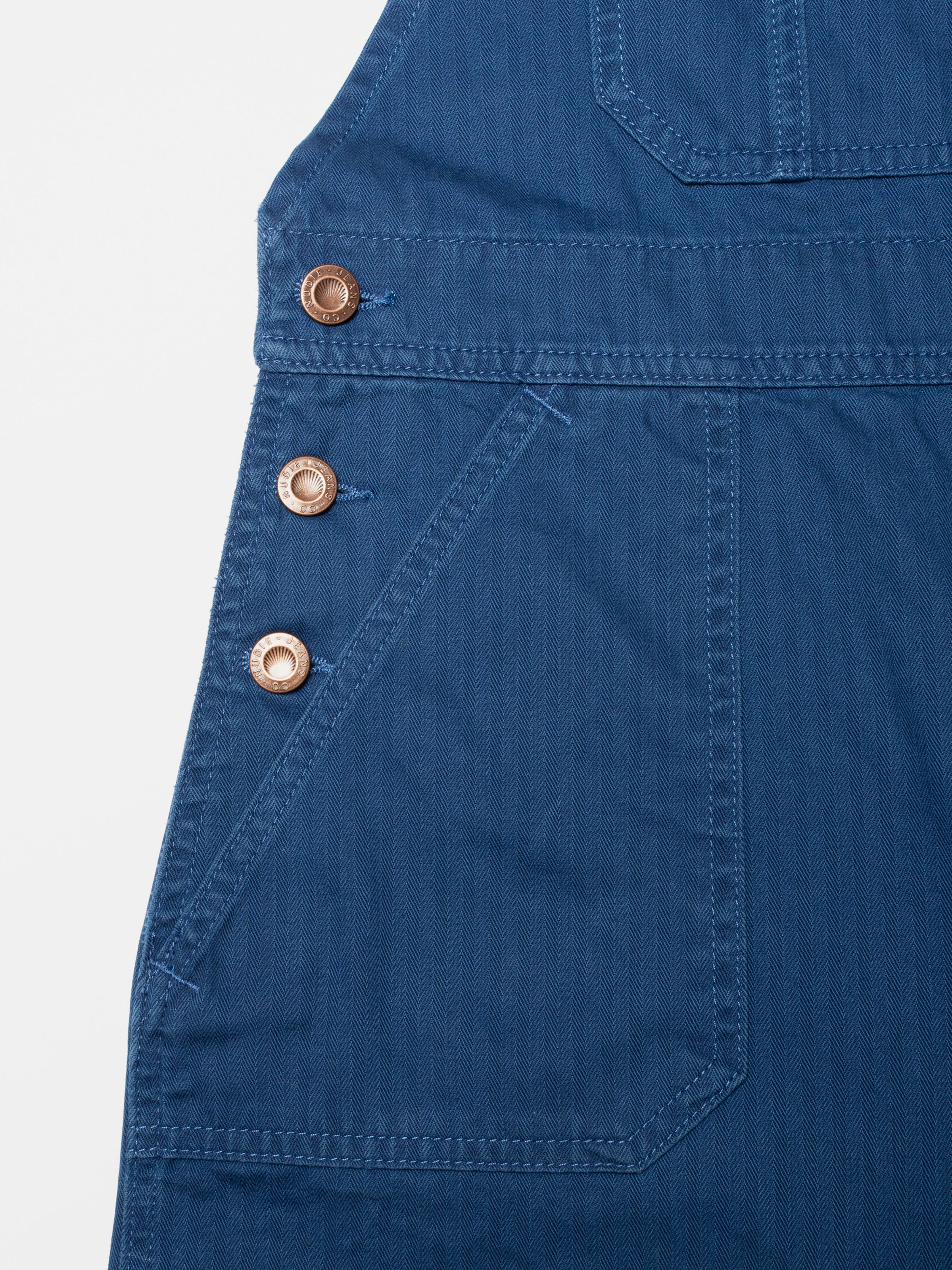 Nudie Jeans Klara Dungarees Herringbone, dungarees in blue, showing a close-up of the side buttons and herringbone fabric.
