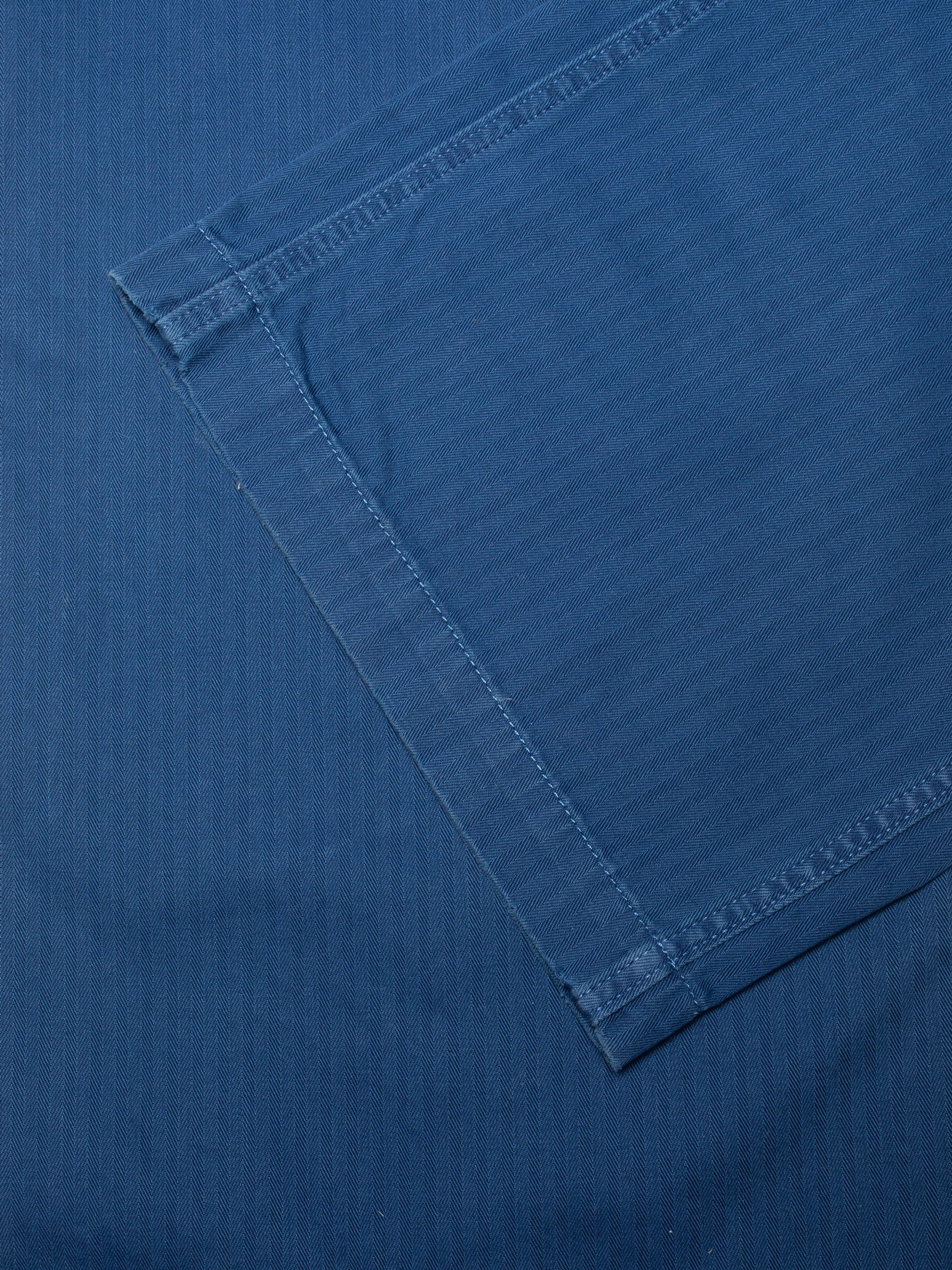 Nudie Jeans Klara Dungarees Herringbone, close-up of the leg hem showing the blue herringbone twill fabric.