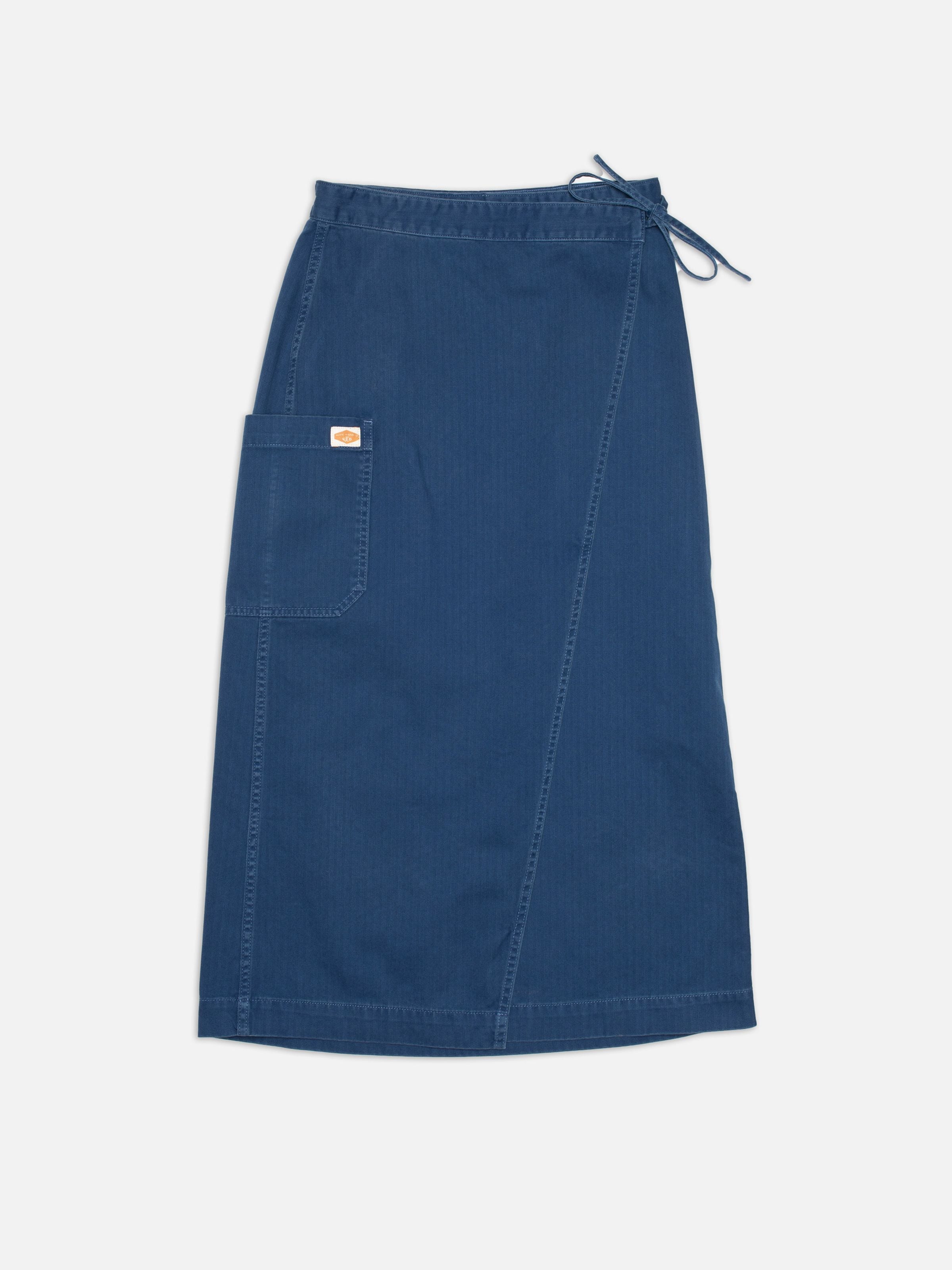 Nudie Jeans Irma Skirt Herringbone, blauer Damen-Wickelrock aus Fischgrat-Twill, flach von vorne gezeigt.