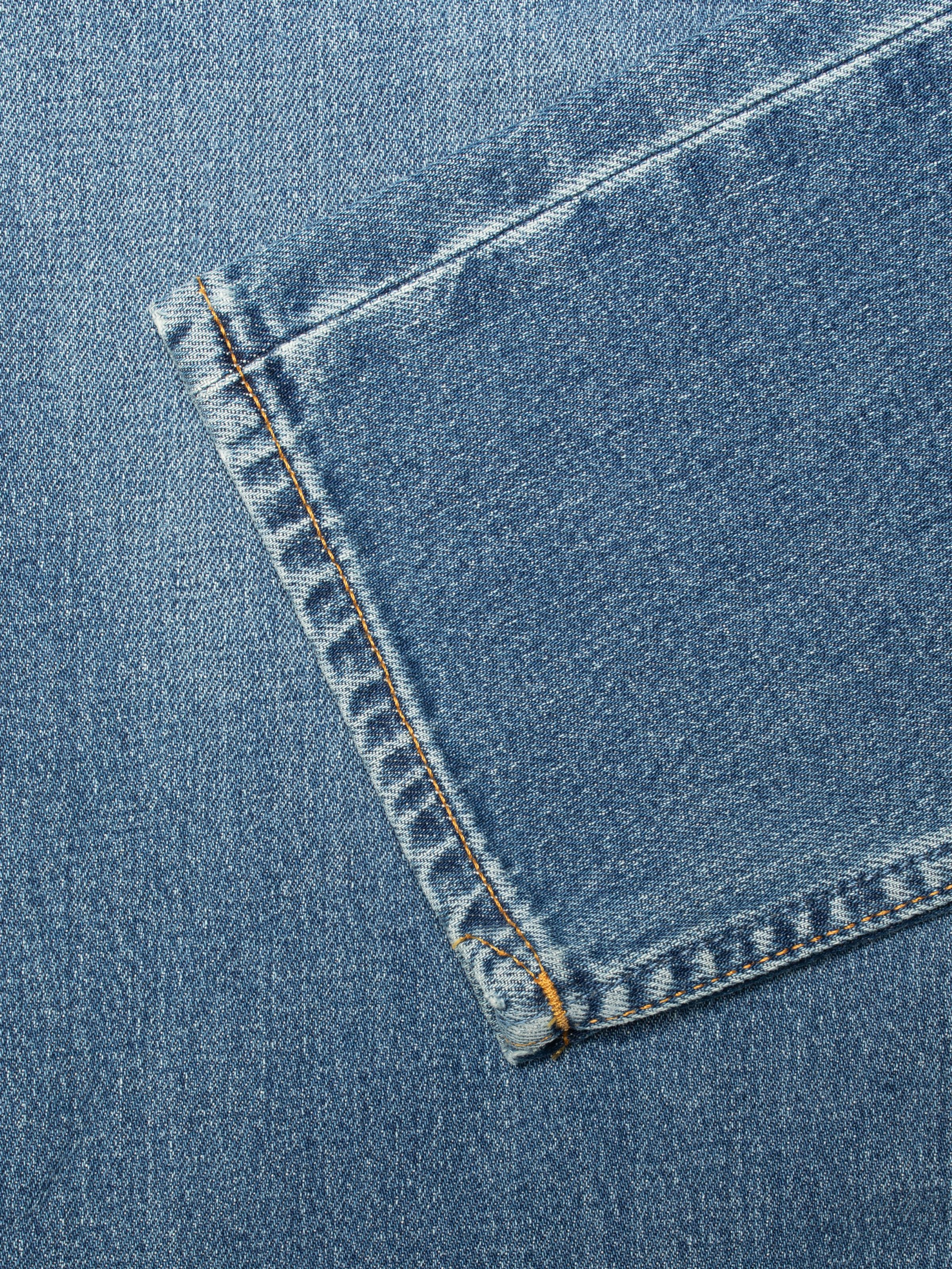 Nudie Jeans Solid Ollie Blue Blur, close-up of the back pocket showing the denim texture and tobacco thread stitching.