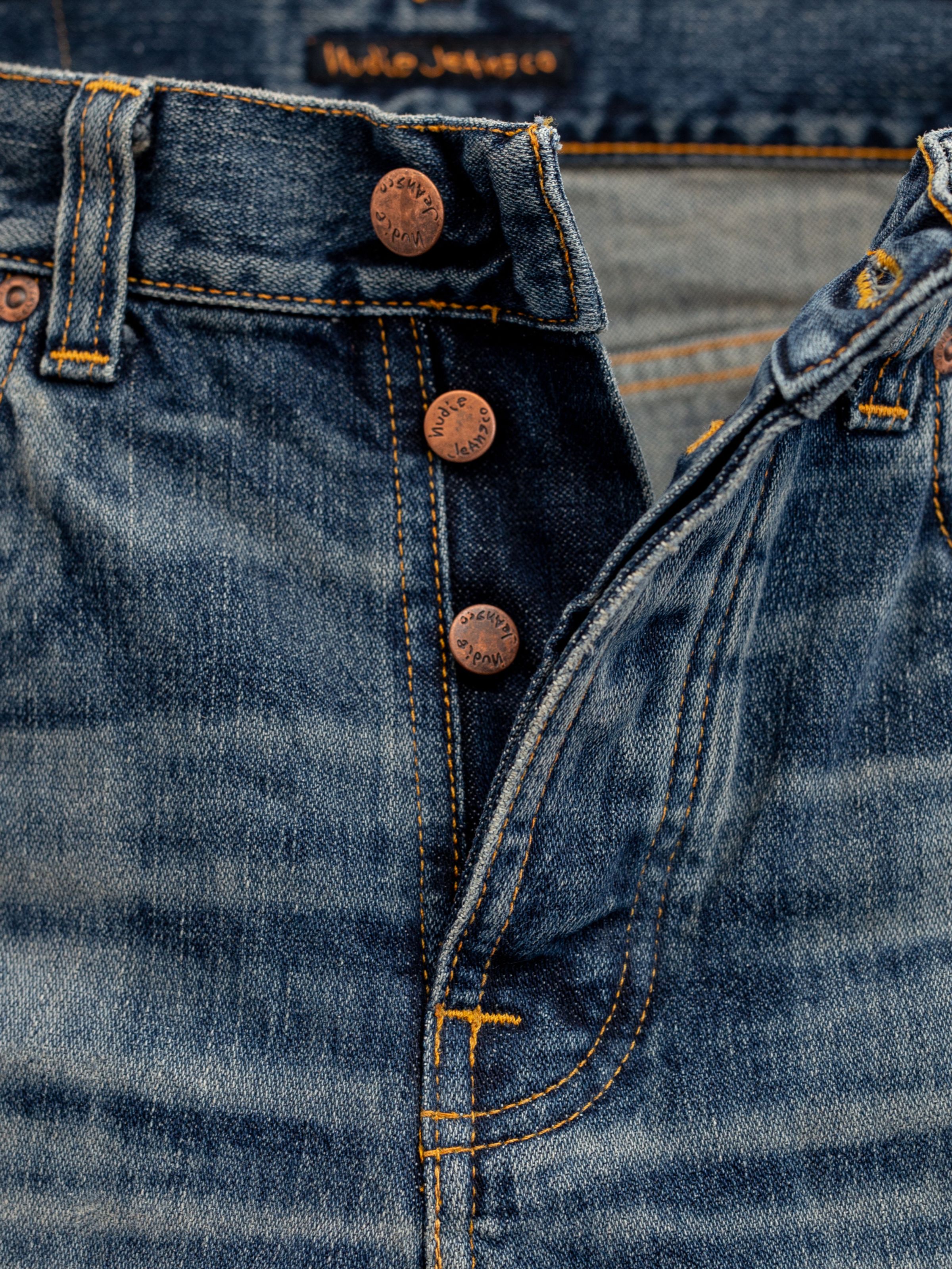 Nudie Jeans Rad Rufus Sand Tracks, men's regular fit jeans, showing a close-up of the button fly and copper trims.