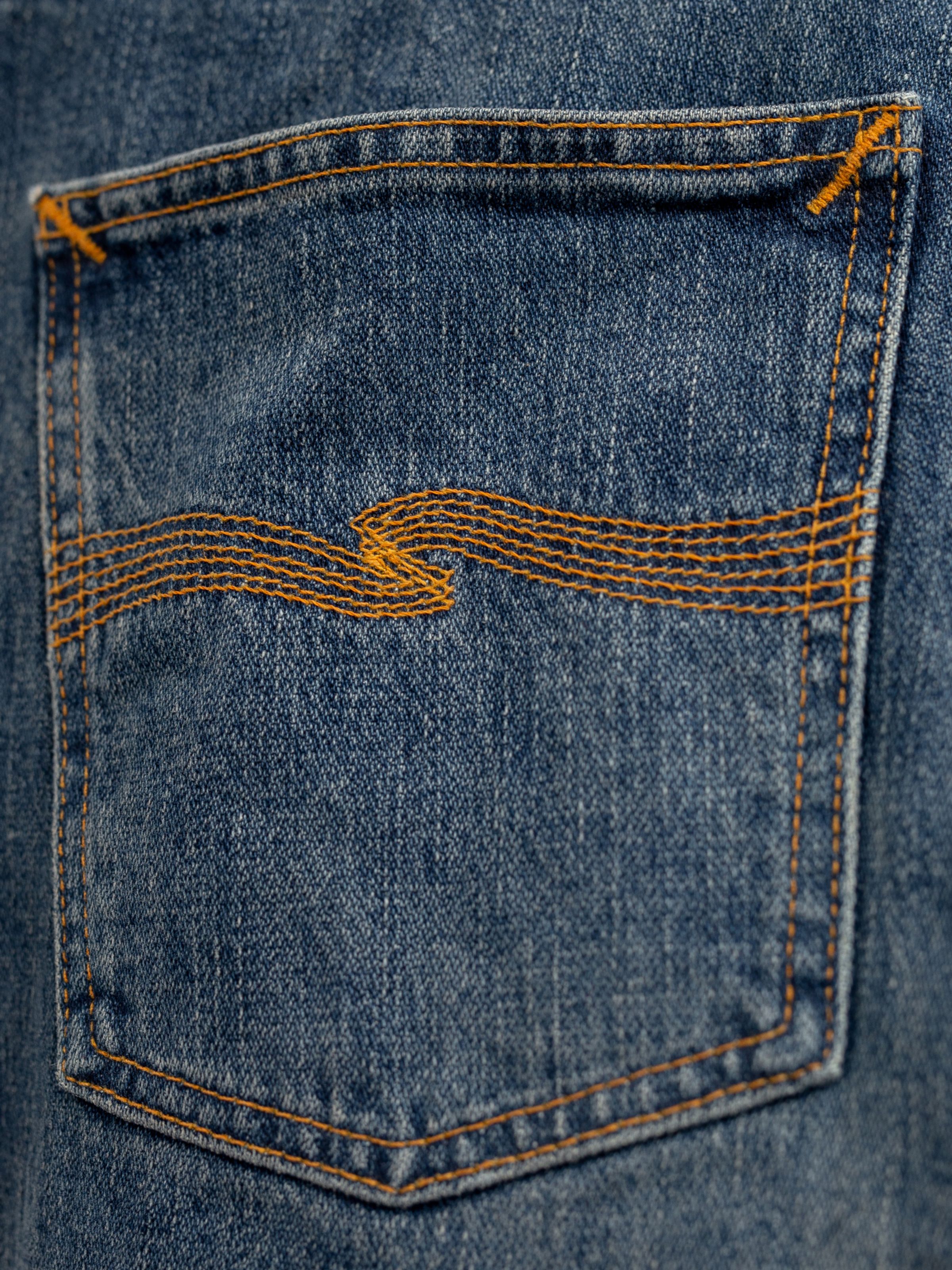 Nudie Jeans Rad Rufus Sand Tracks, men's regular fit jeans, showing a close-up of the back pocket with orange embroidery.