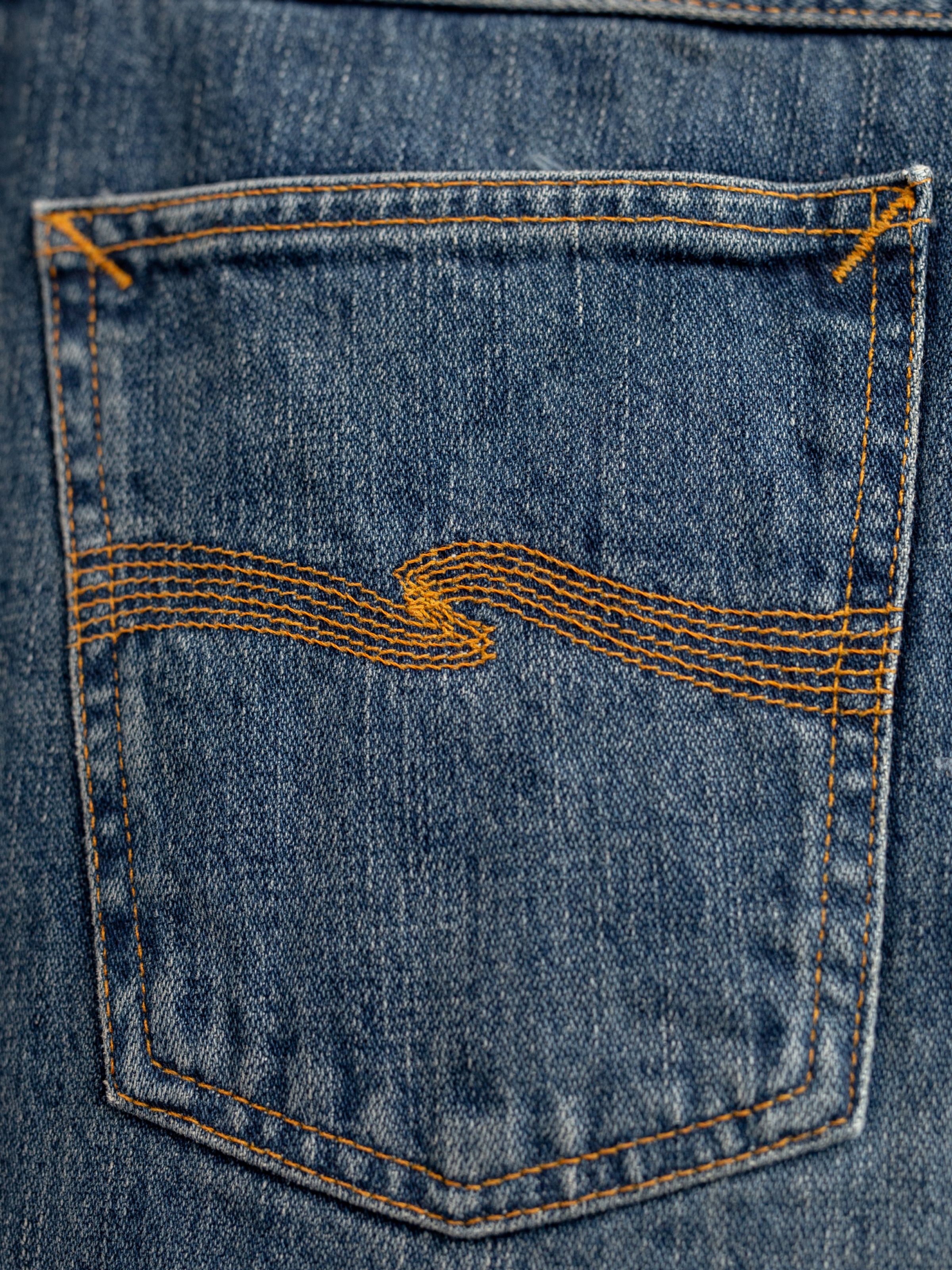 Nudie Jeans Gritty Jackson Sand Tracks, men's regular fit jeans, close-up of the back pocket with signature stitching.