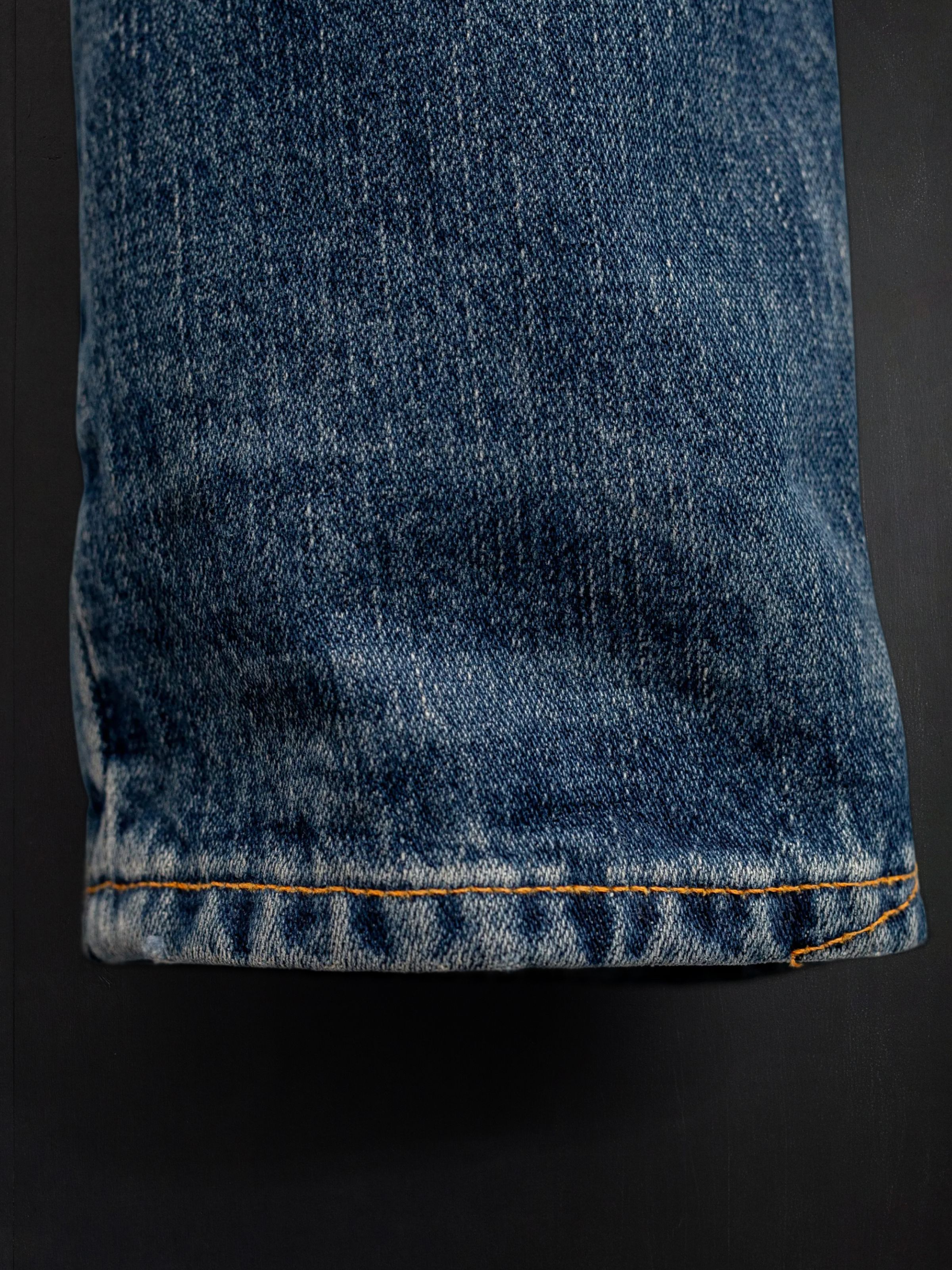 Nudie Jeans Gritty Jackson Sand Tracks, men's regular fit jeans, showing a close-up of the hem and denim texture.