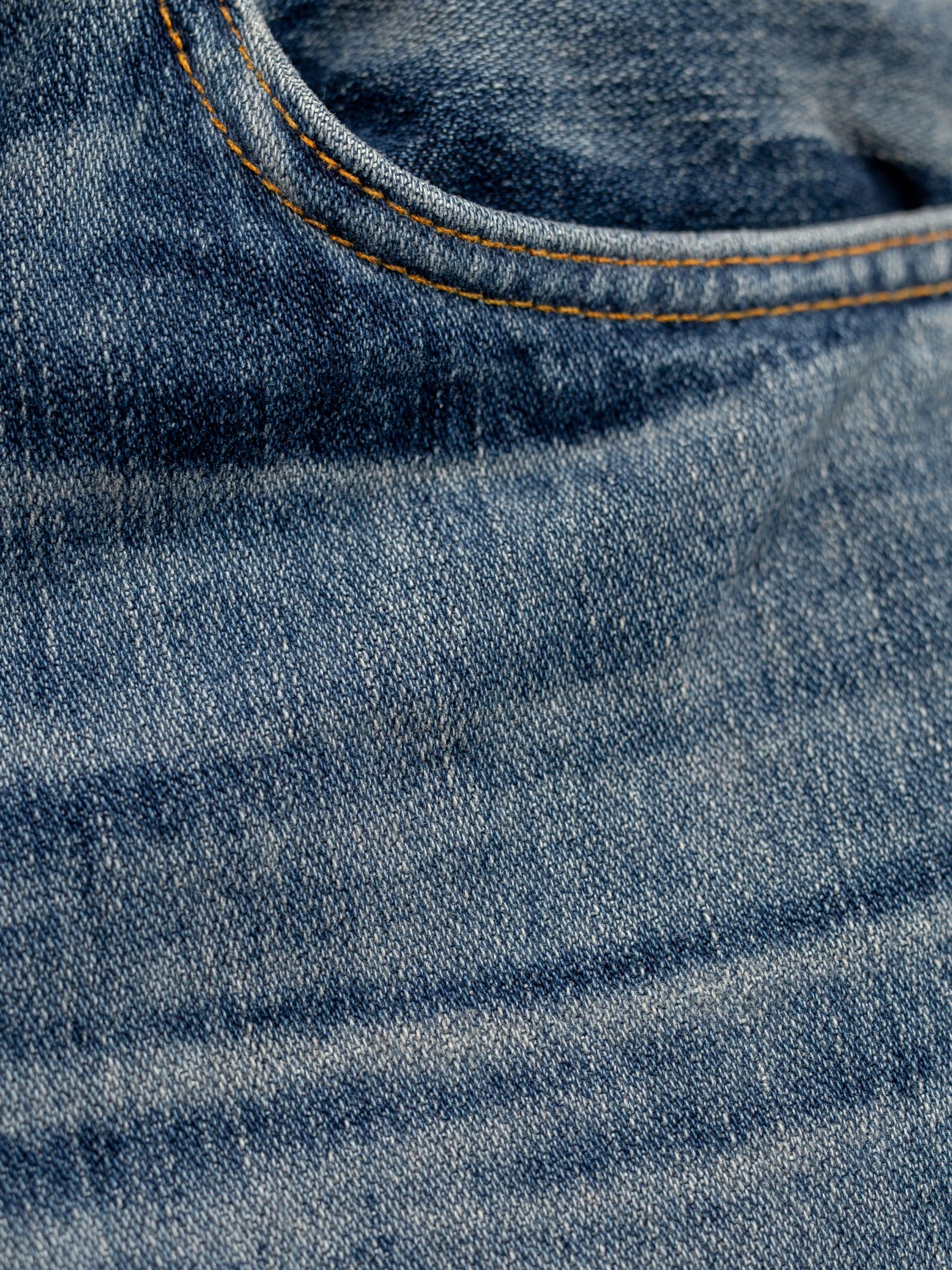 Nudie Jeans Gritty Jackson Sand Tracks, men's regular fit jeans, showing a close-up of the front pocket and denim texture.