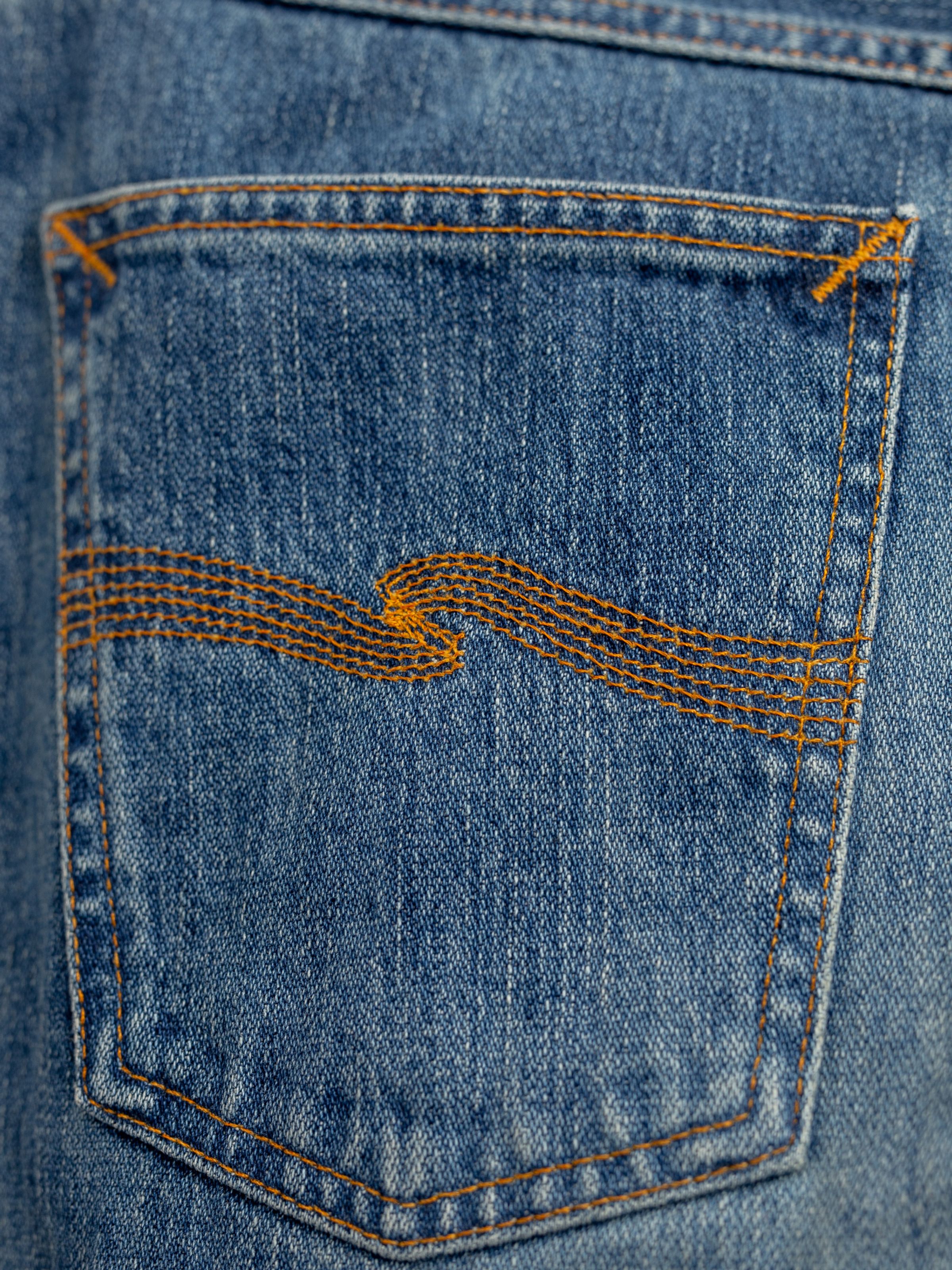 Nudie Jeans Steady Eddie II Muted Tracks, men's regular fit tapered jeans, close-up of the back pocket embroidery.