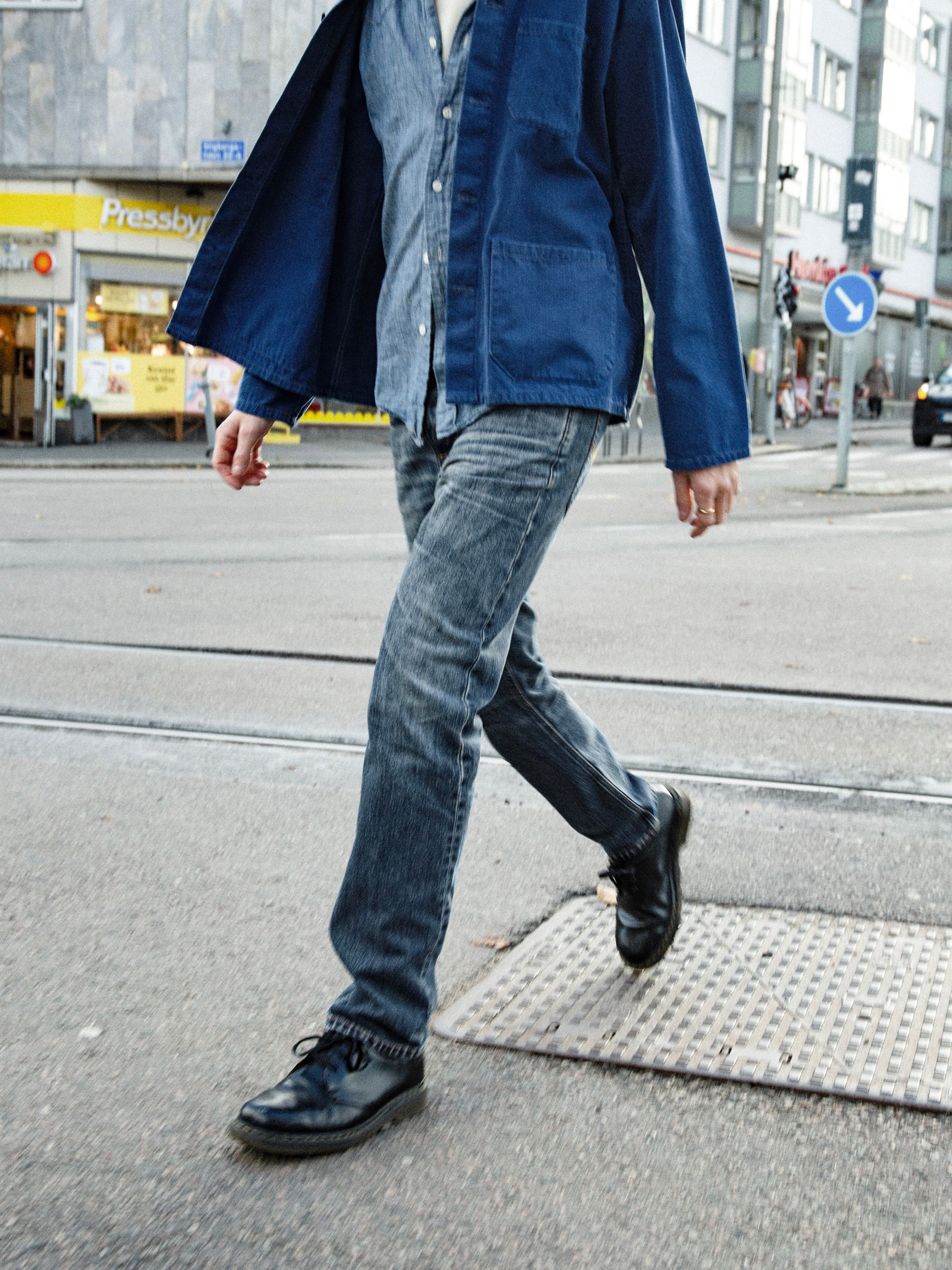 Nudie Jeans Steady Eddie II Muted Tracks, men's regular tapered jeans, shown on a model walking across a city street.