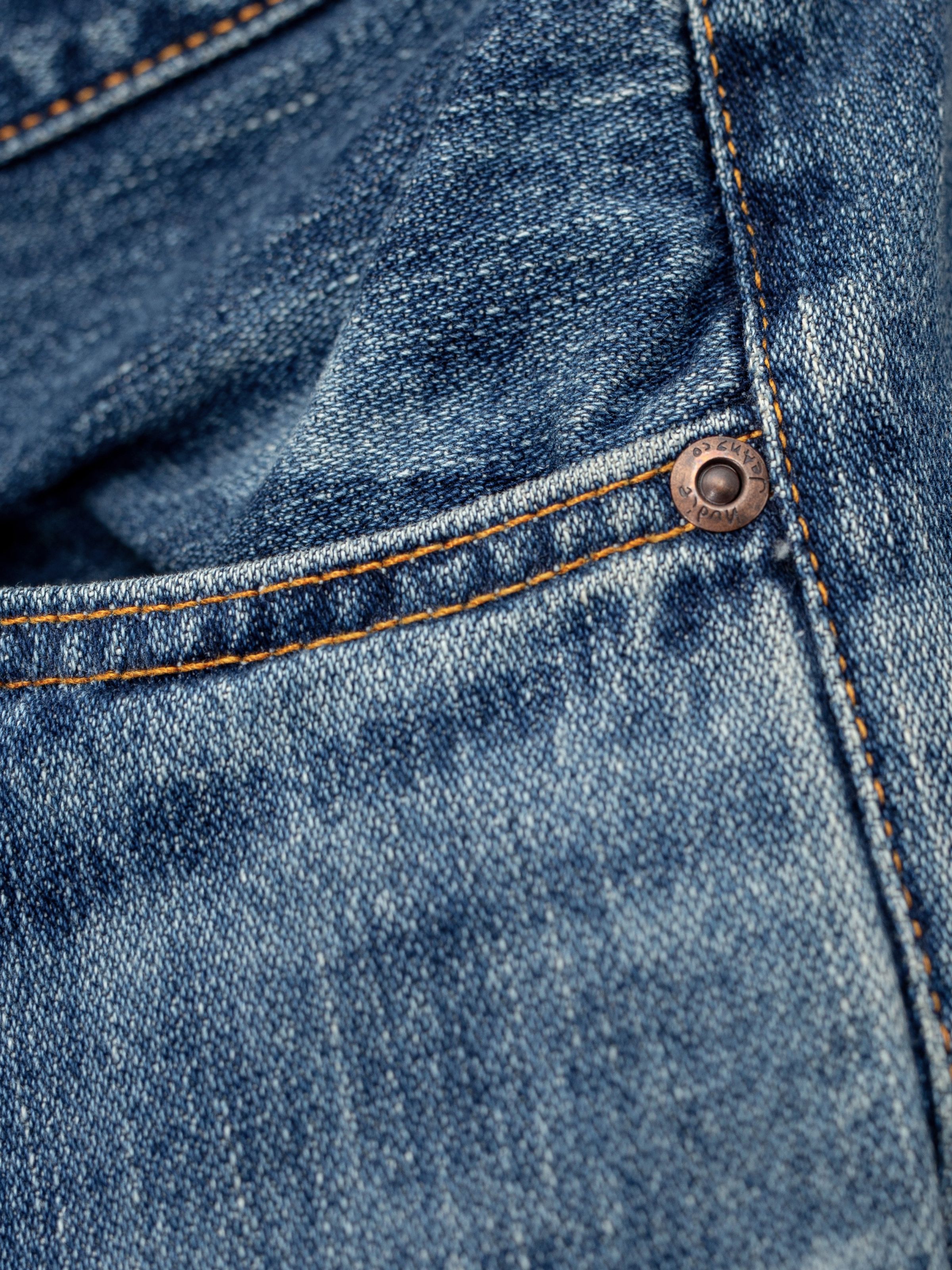 Nudie Jeans Steady Eddie II Muted Tracks, men's regular tapered jeans, close-up of the front pocket and copper rivet.
