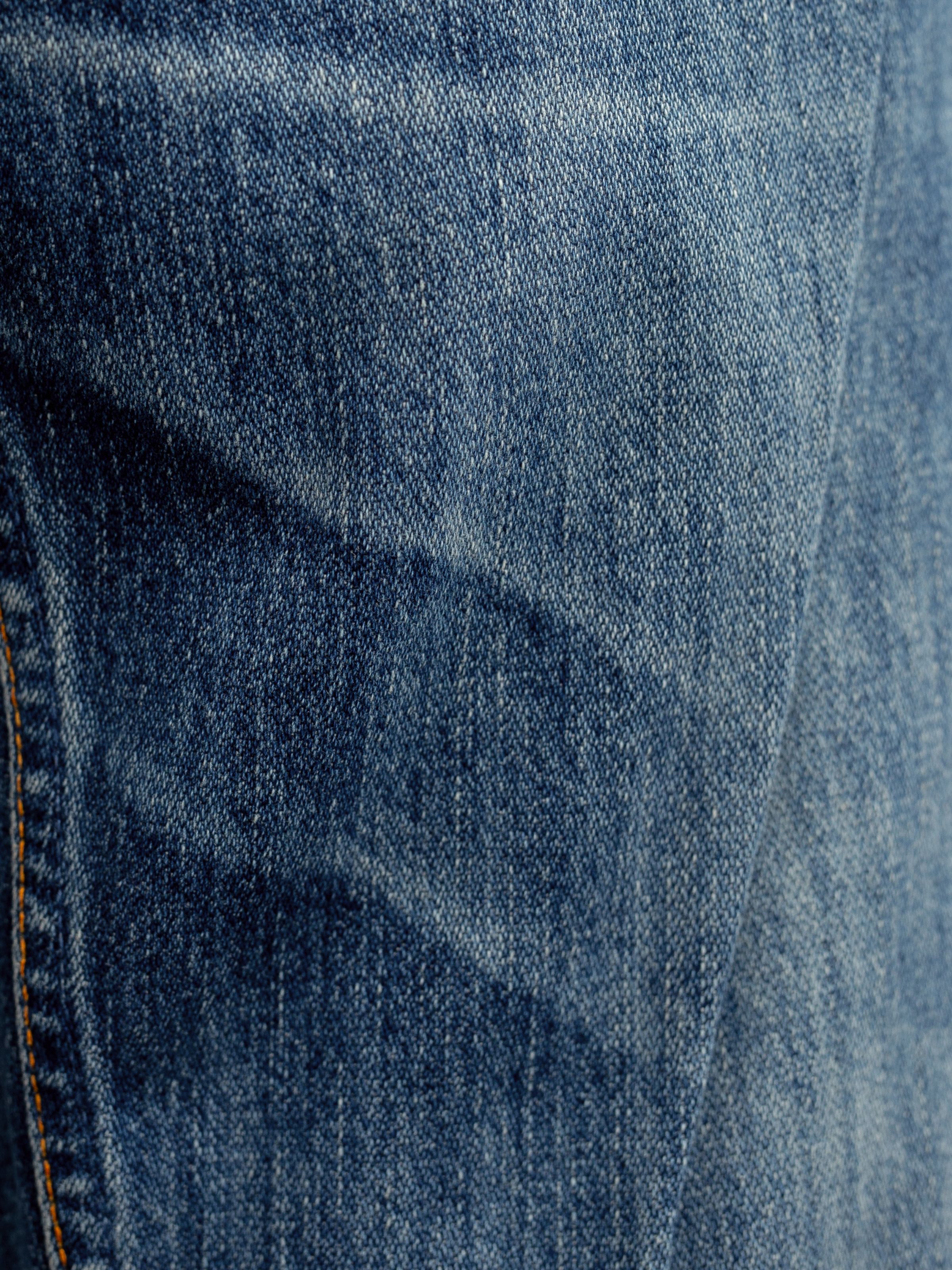 Nudie Jeans Steady Eddie II Muted Tracks, men's regular tapered fit jeans, close-up of the mid-blue broken twill denim.