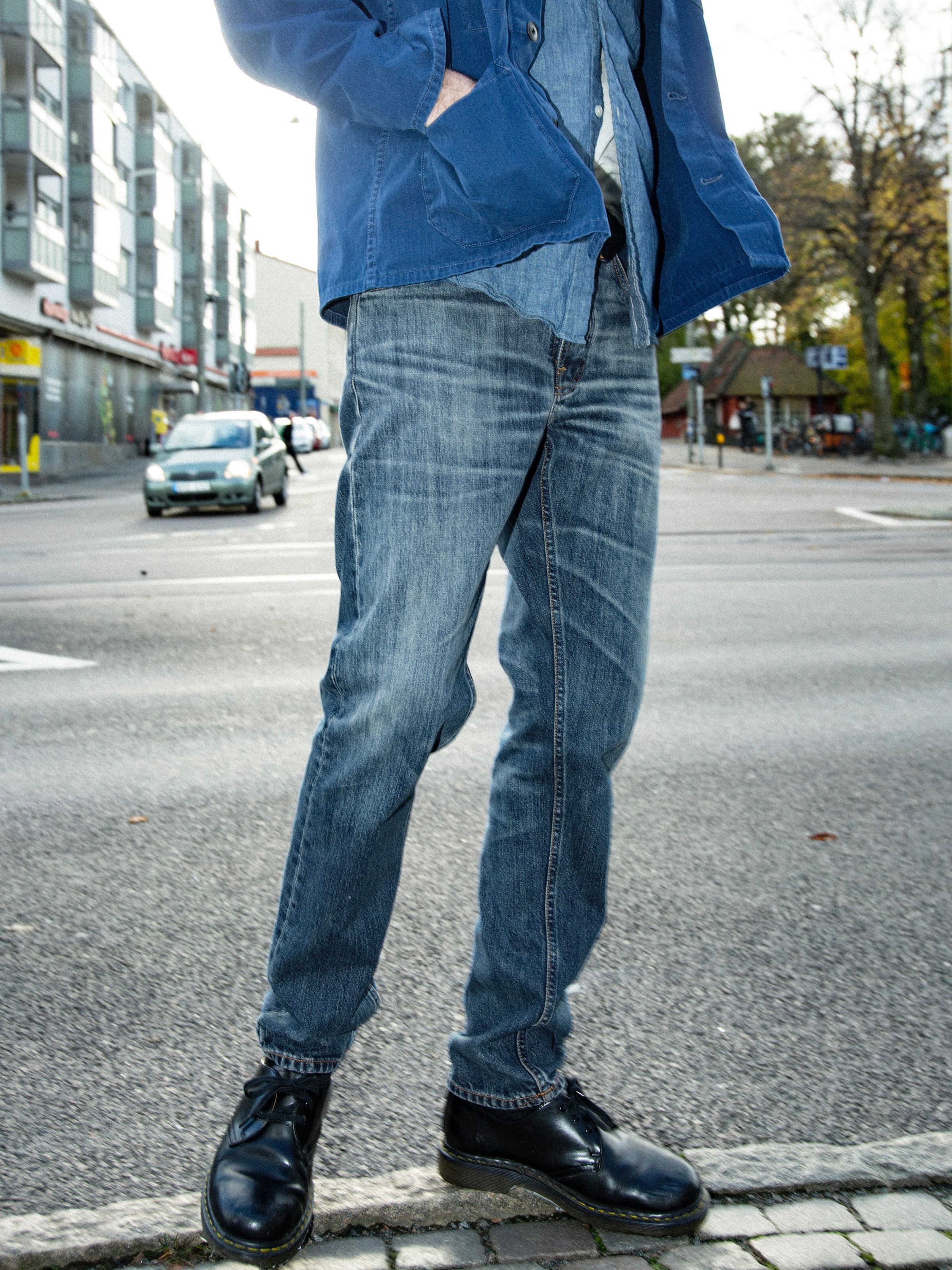 Nudie Jeans Steady Eddie II Muted Tracks, men's regular tapered fit jeans shown on a model from the waist down on a street.