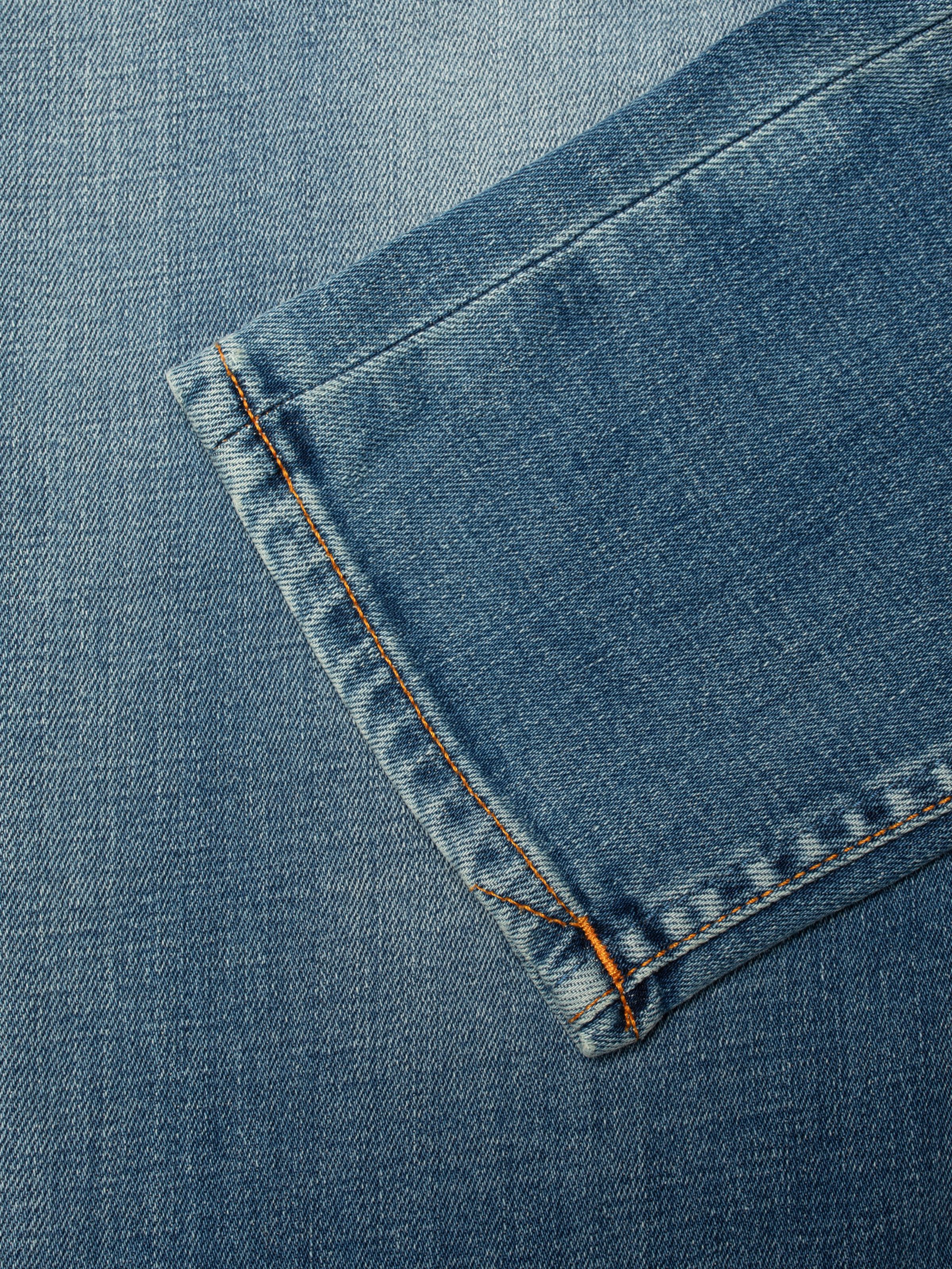 Nudie Jeans Lean Dean Blue Legend, close-up of the hem showing the denim texture and orange thread detail.