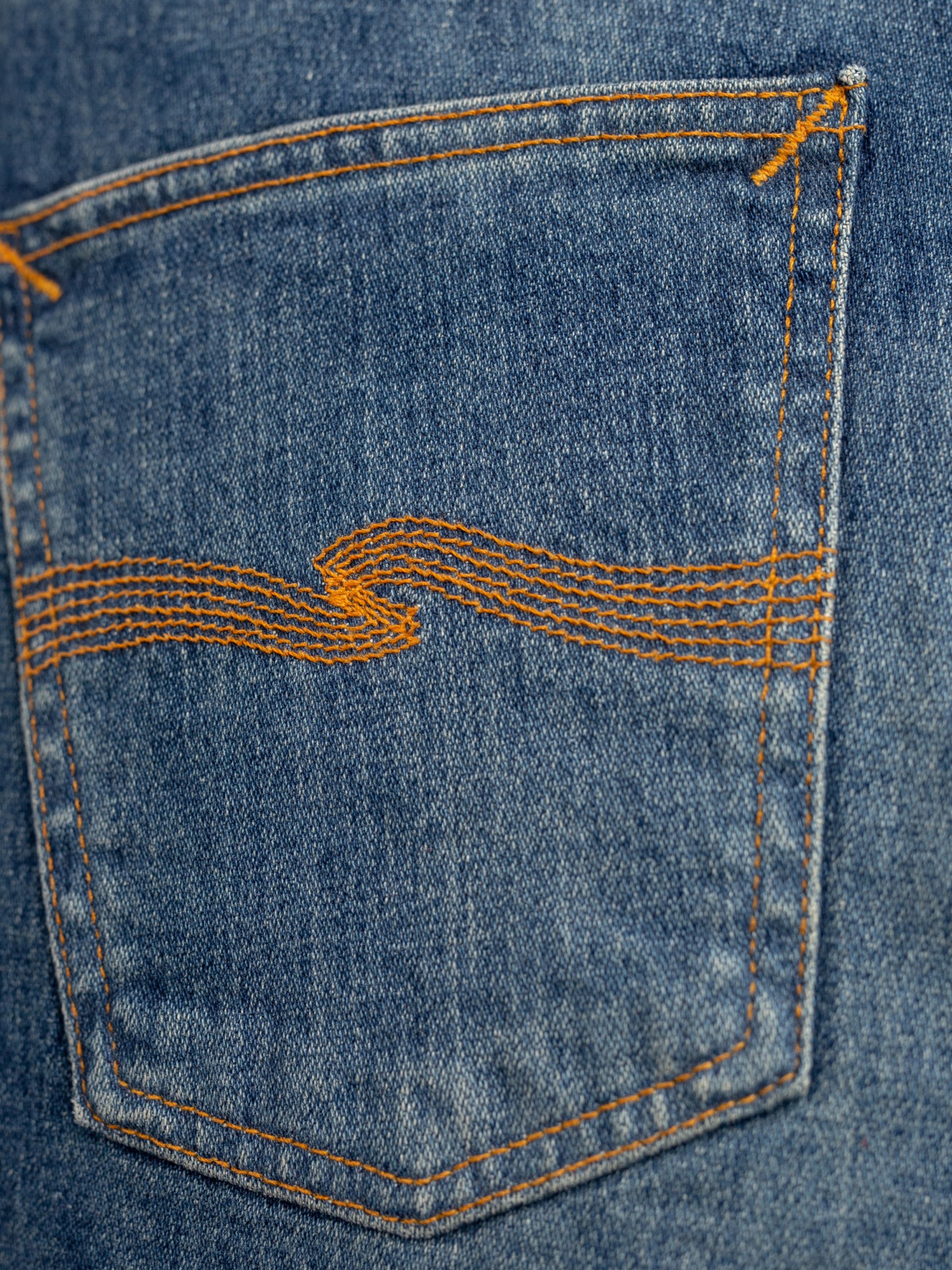 Nudie Jeans Lean Dean Salty Tracks, men's slim tapered jeans, showing a close-up of the back pocket with orange embroidery.