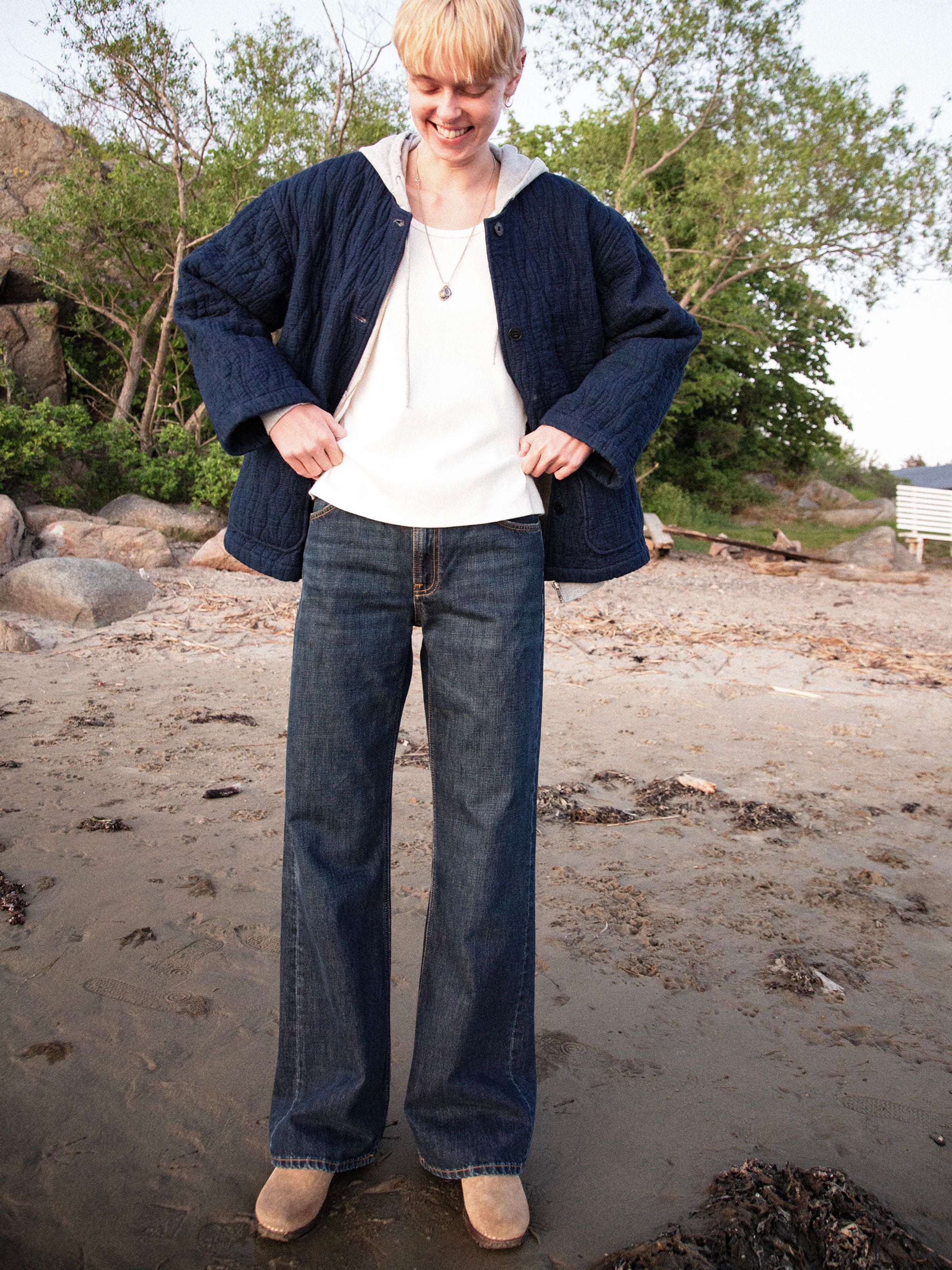 Nudie Jeans Wide Heidi Warm Wave, Damenjeans mit weitem Bein, von einem Model am Strand von vorne gezeigt.