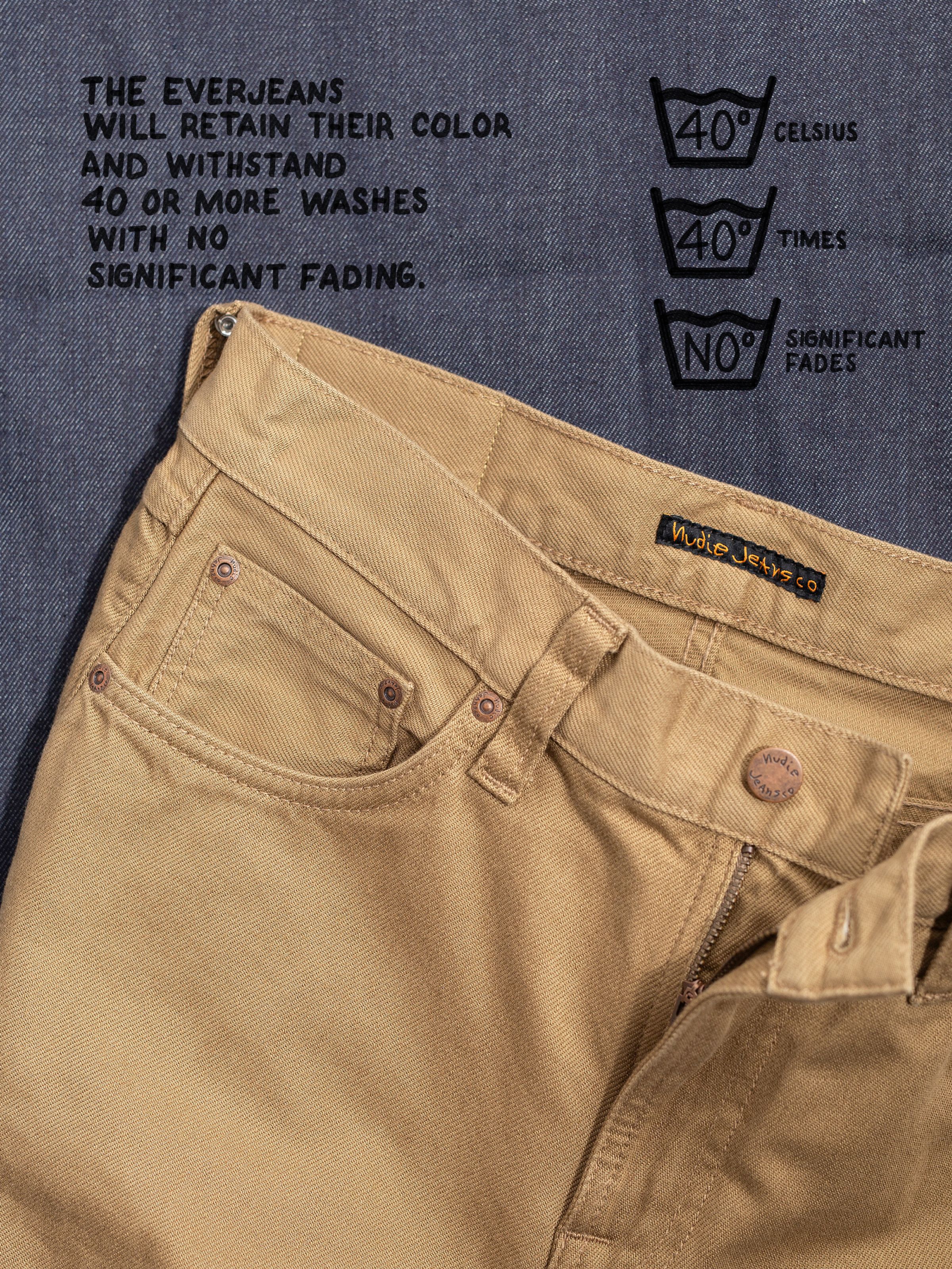 Nudie Jeans Gritty Jackson Everlion in tobacco, close-up of the waistband with text explaining the fabric's color retention.