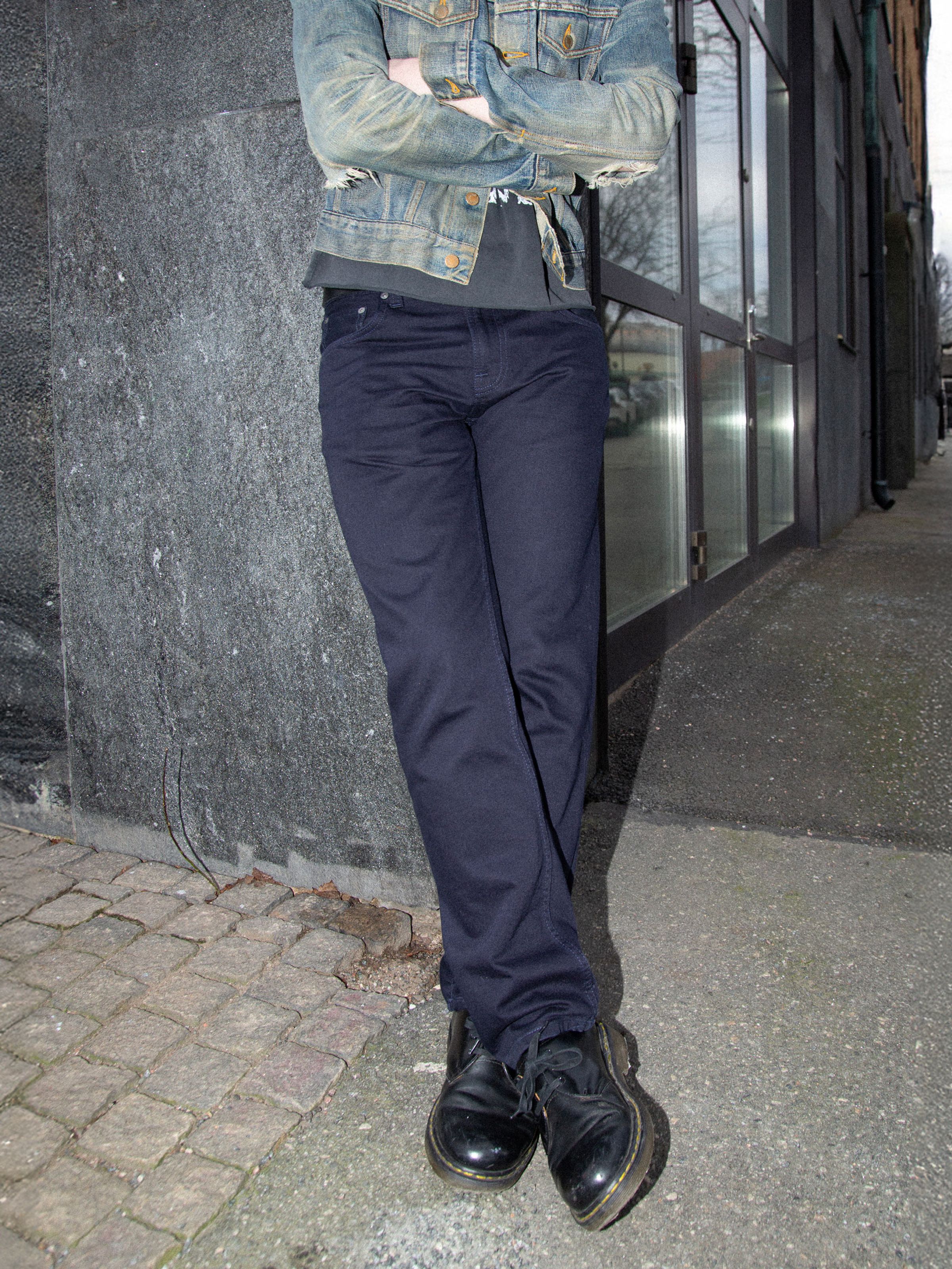 Nudie Jeans Gritty Jackson Everblue, men's regular fit straight jeans shown from the front on a model leaning against a wall.