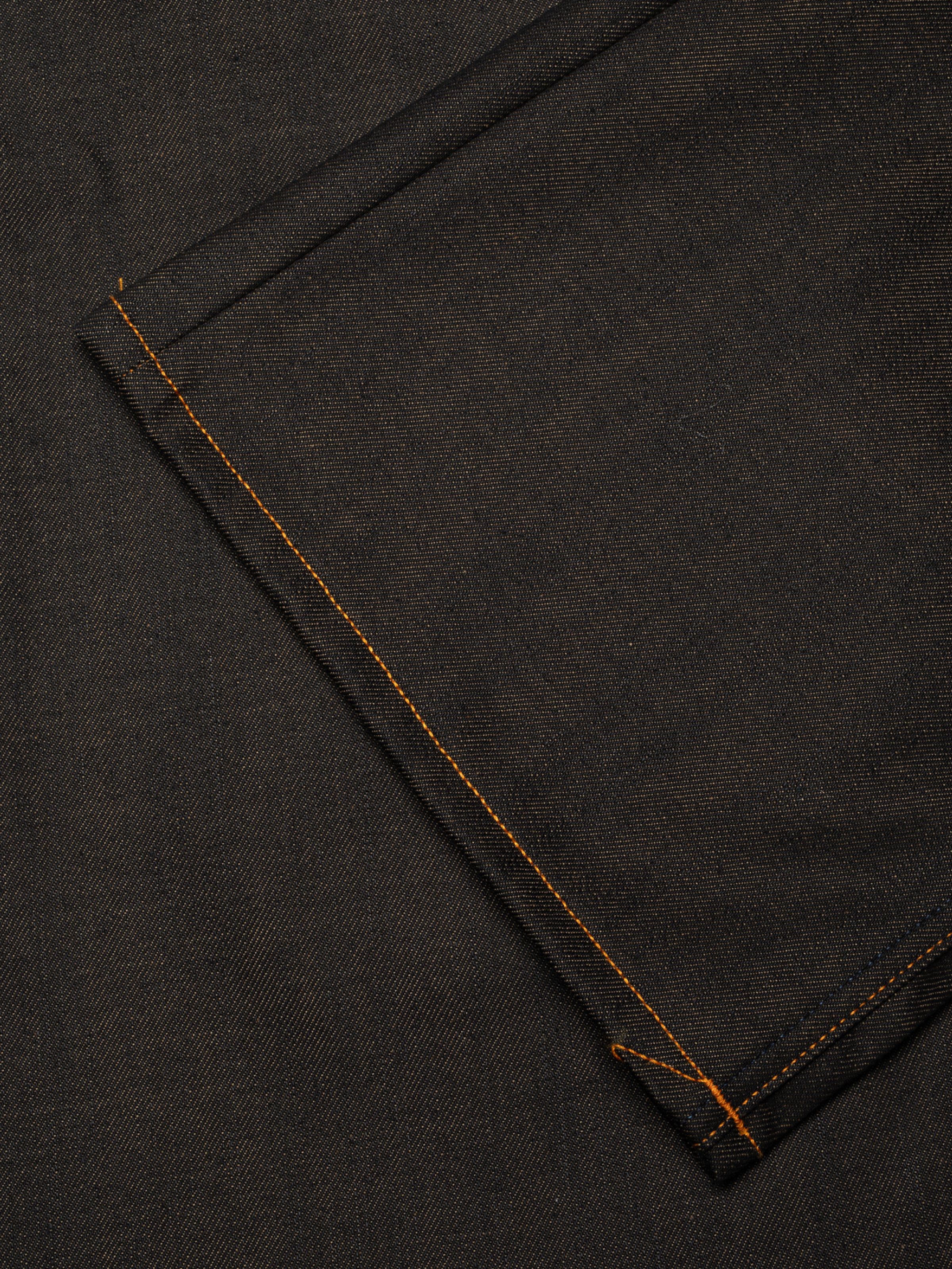 Nudie Jeans Wide Heidi in Dry Blue, eine Nahaufnahme des dunklen Rigid Denims und der orangefarbenen Nähte am Saum.