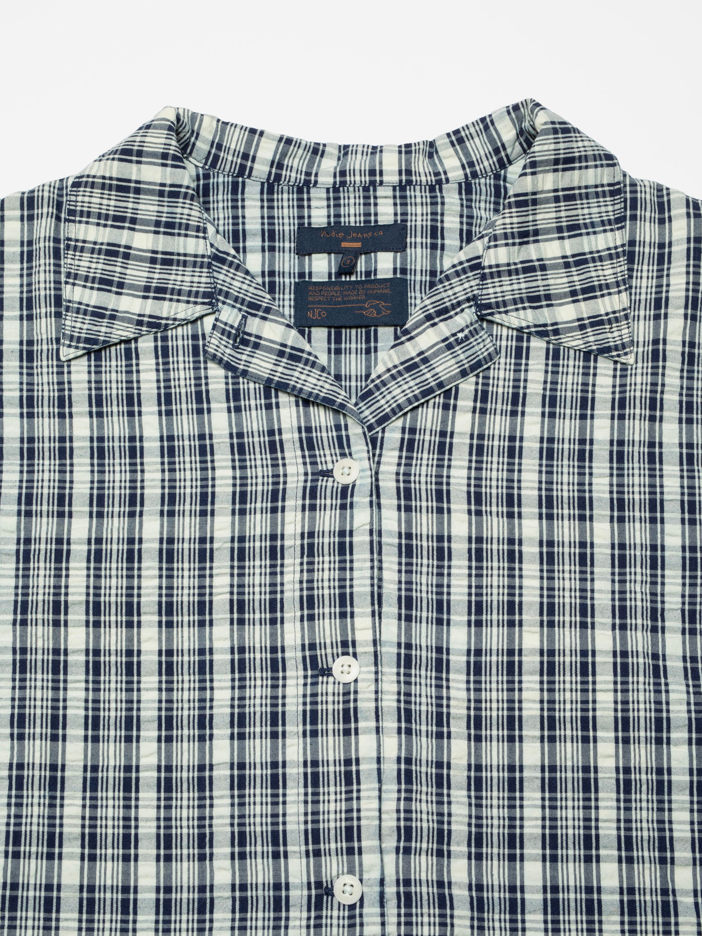 Nudie Jeans Jutta Shirt Indigo Seersucker, close-up of the open collar and checkered seersucker texture.