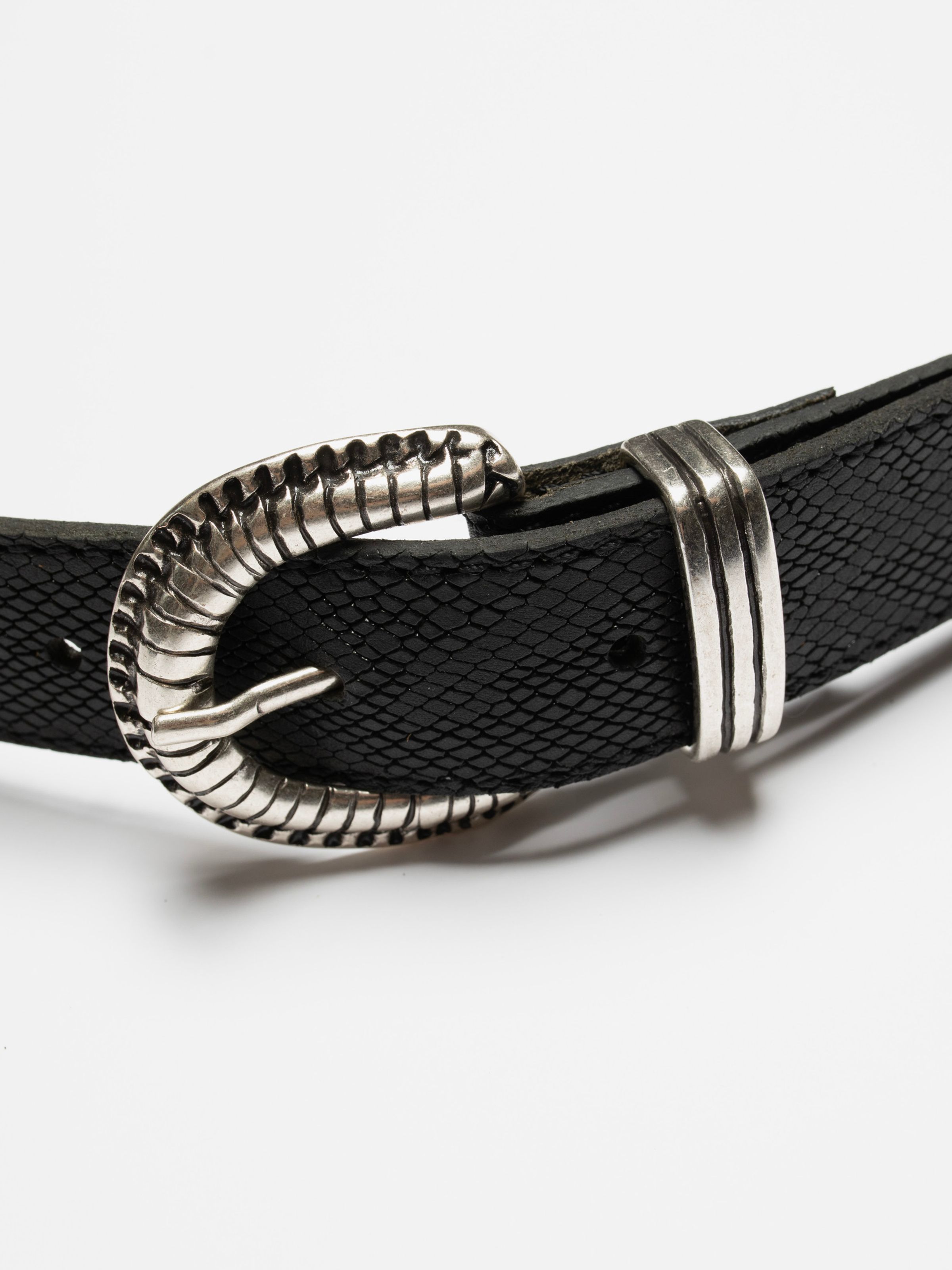 Nudie Jeans Faux Reptile Leather Belt in Black, close-up of the antique silver buckle and reptile-embossed leather.
