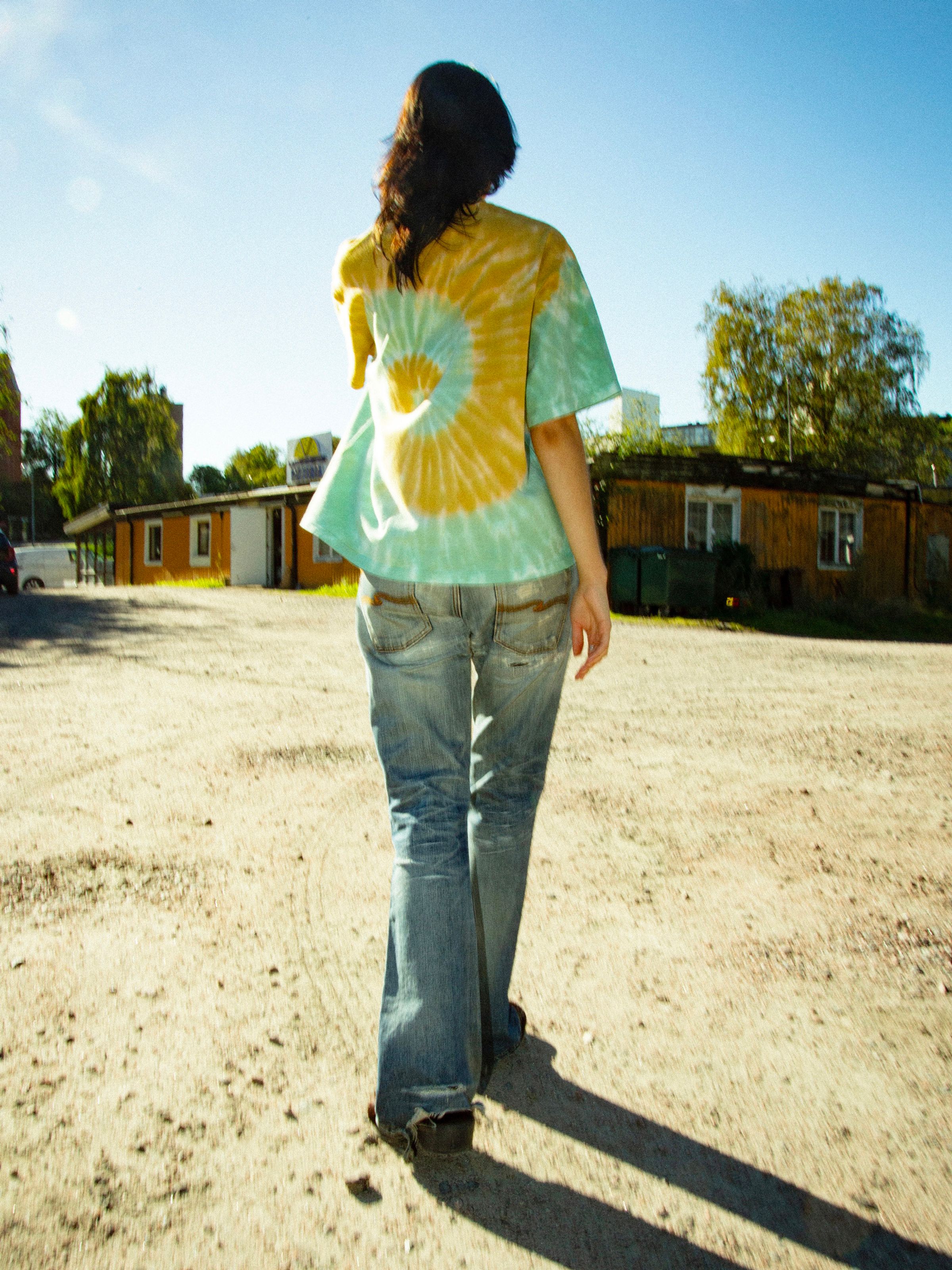 Nudie Jeans Rita T-Shirt Take It Easy, women's organic cotton tie-dye t-shirt shown from the back on a model outdoors.