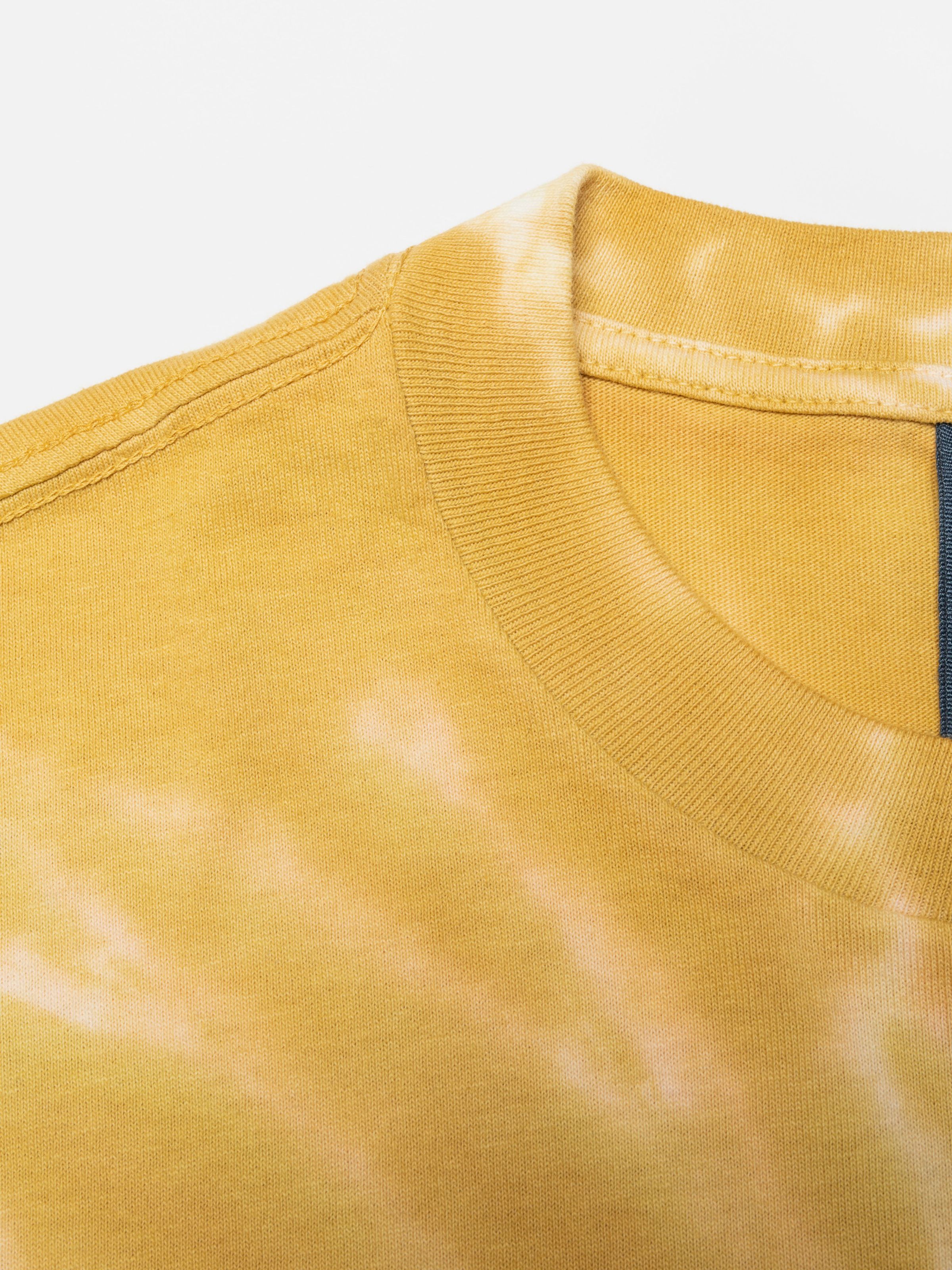 Nudie Jeans Rita T-Shirt Take It Easy, close-up of the ribbed crew-neck and yellow tie-dye organic cotton jersey.