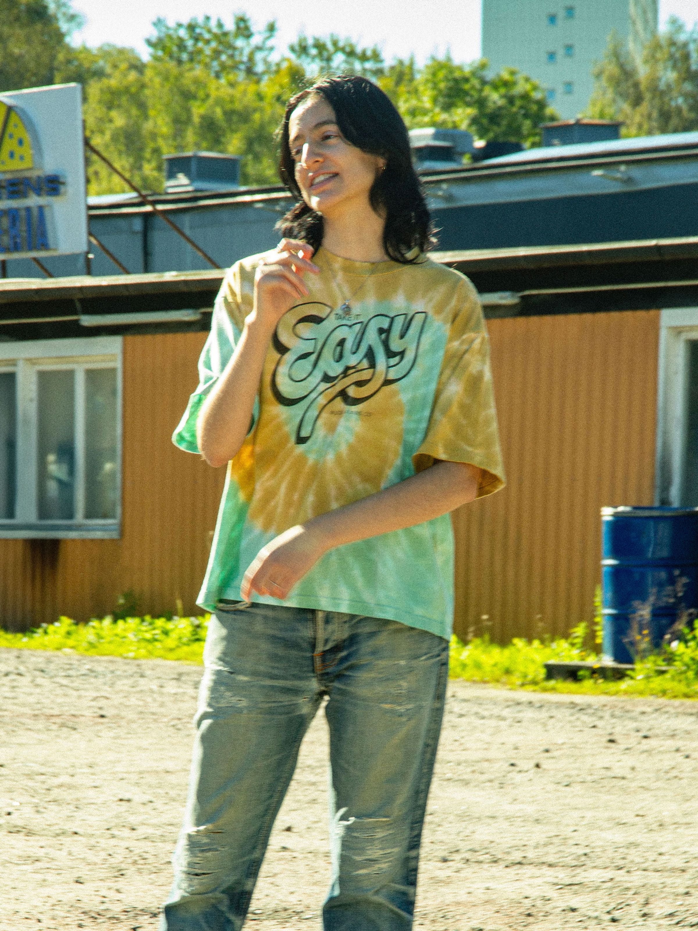 Nudie Jeans Rita T-Shirt Take It Easy, Tie-Dye-T-Shirt für Damen, von vorne an einem Model im Freien gezeigt.