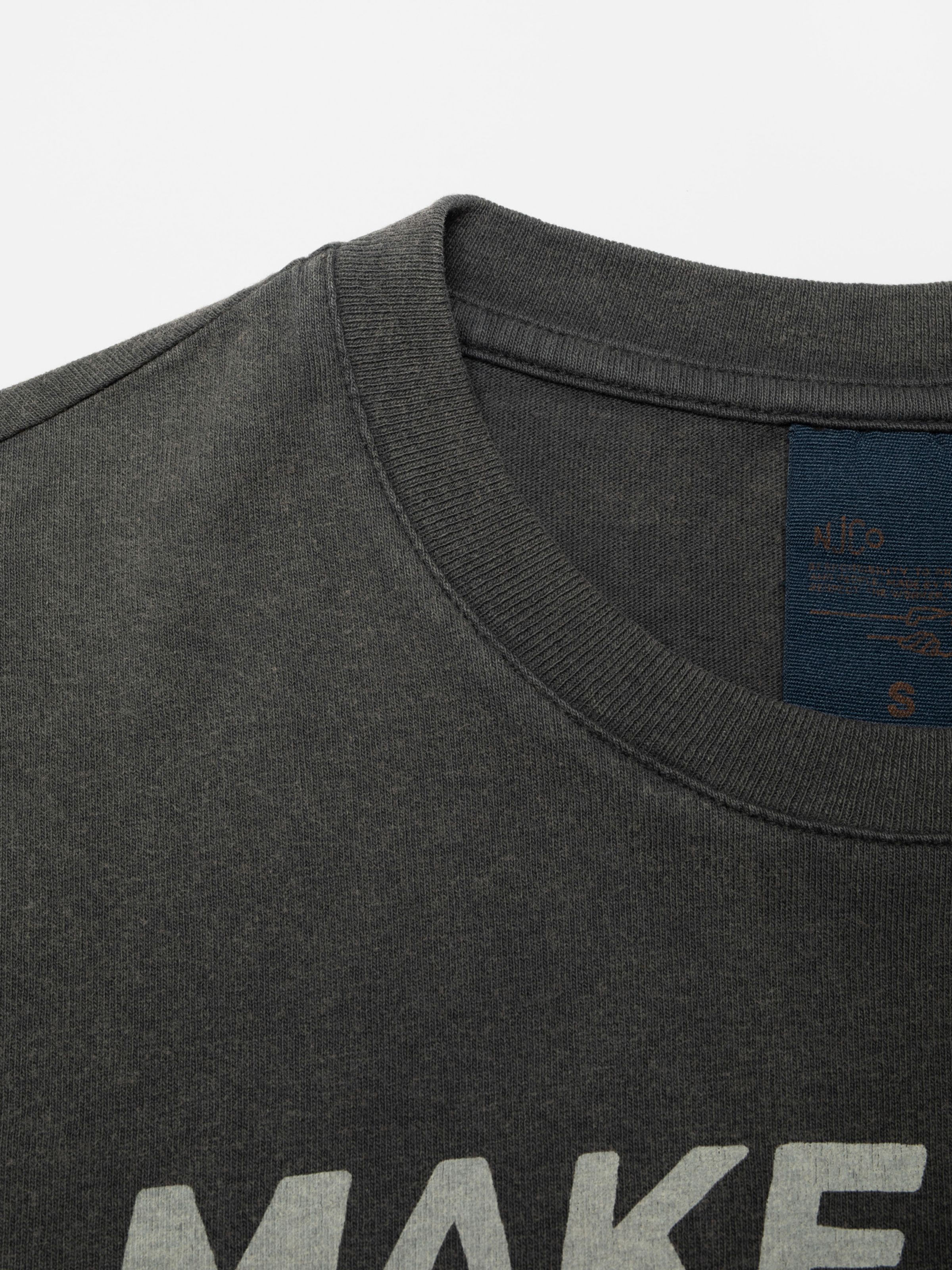Nudie Jeans Joni T-Shirt Make Sense in Antracite, a close-up of the ribbed crew neck and organic cotton jersey fabric.