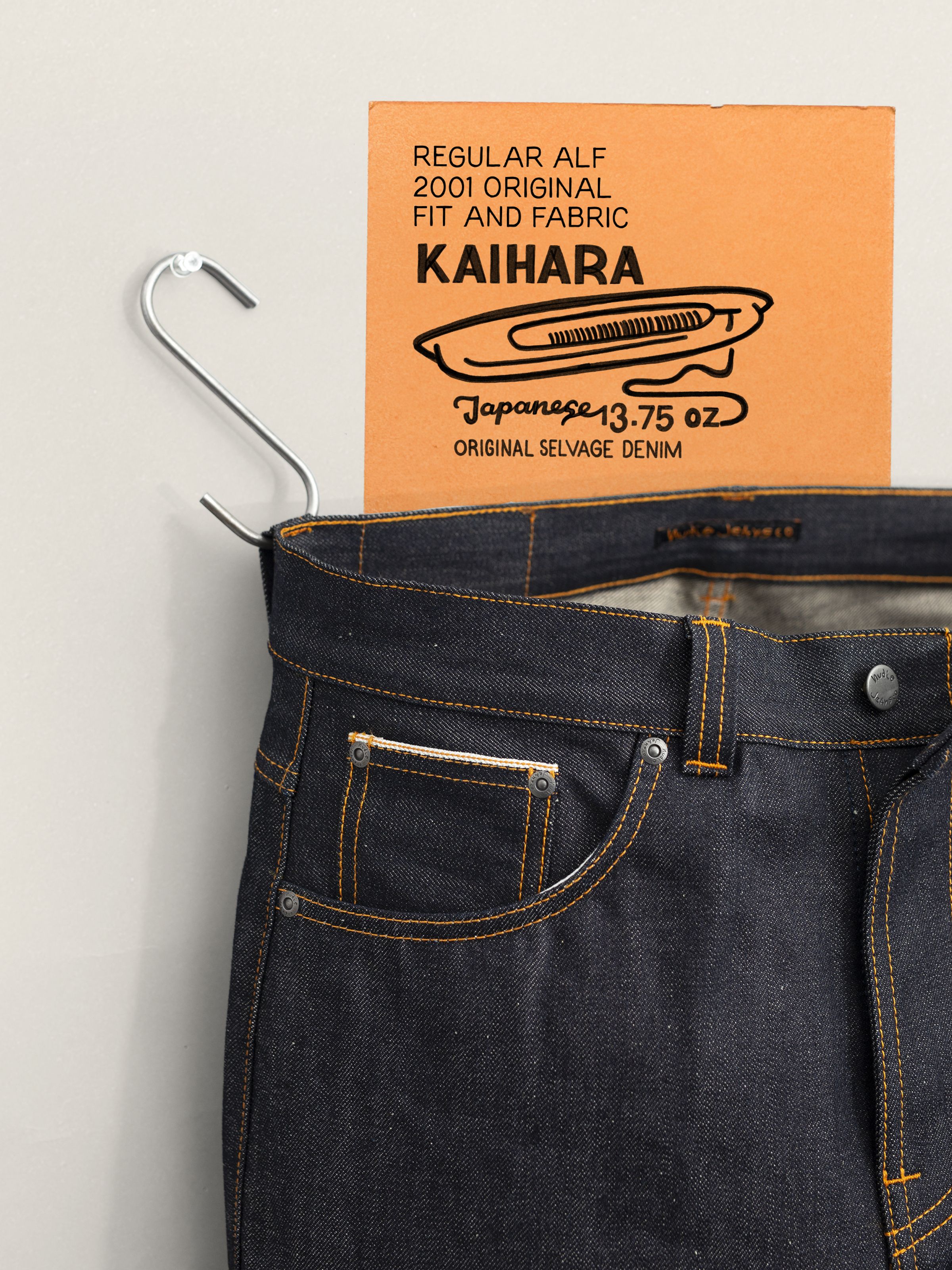 Nudie Jeans Regular Alf Dry Selvage, Nahaufnahme von Hosenbund aus blauem Dry Denim, Münztasche und orangem Kaihara-Tag.