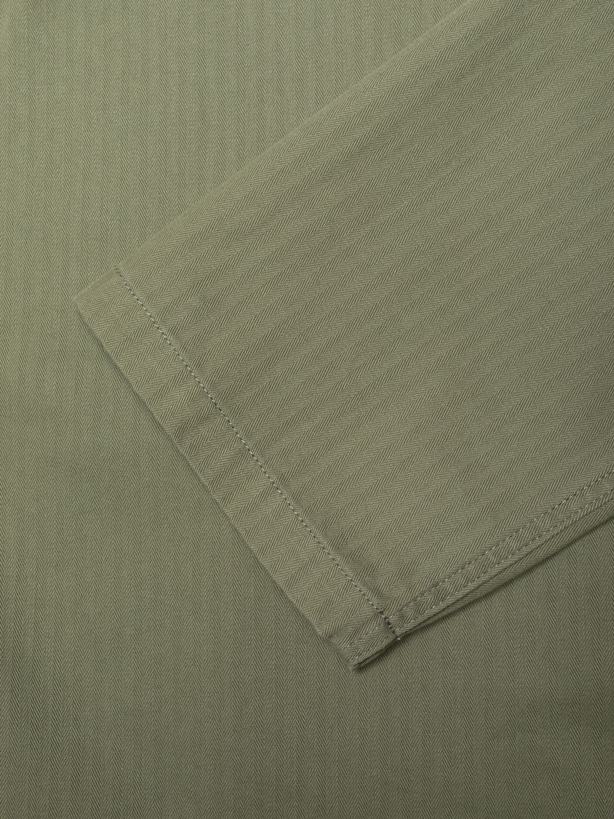 Nudie Jeans Lovis Herringbone Jacket in Pale Green, close-up of the sleeve showing the herringbone twill fabric detail.