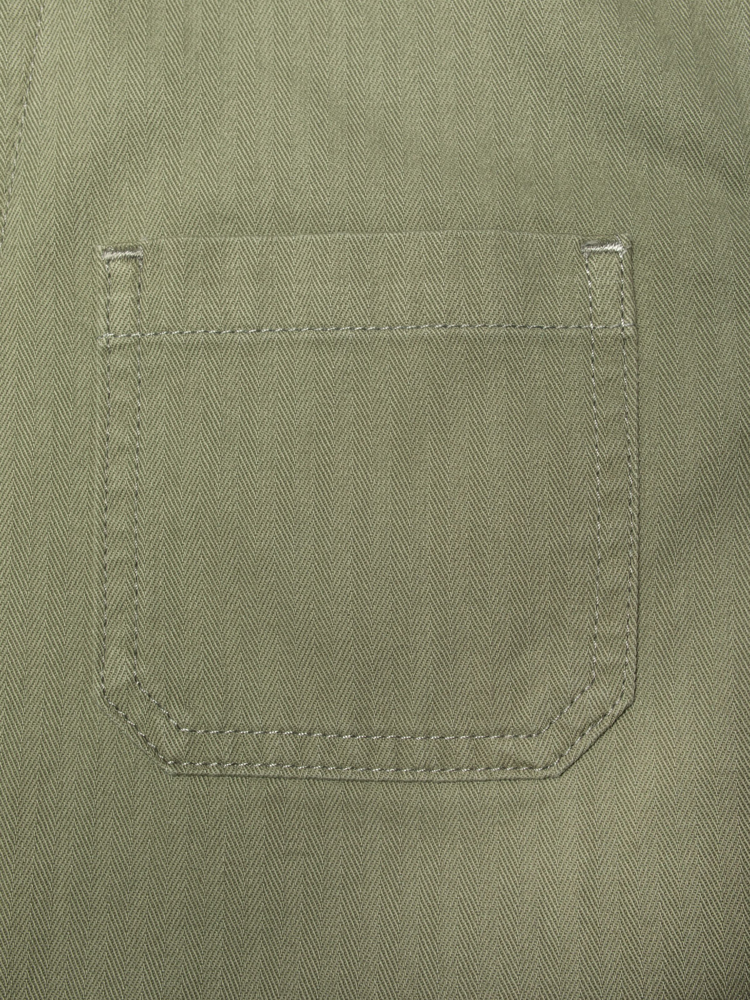 Nudie Jeans Lovis Herringbone Jacket in Pale Green, close-up of the front pocket showing the herringbone twill fabric.