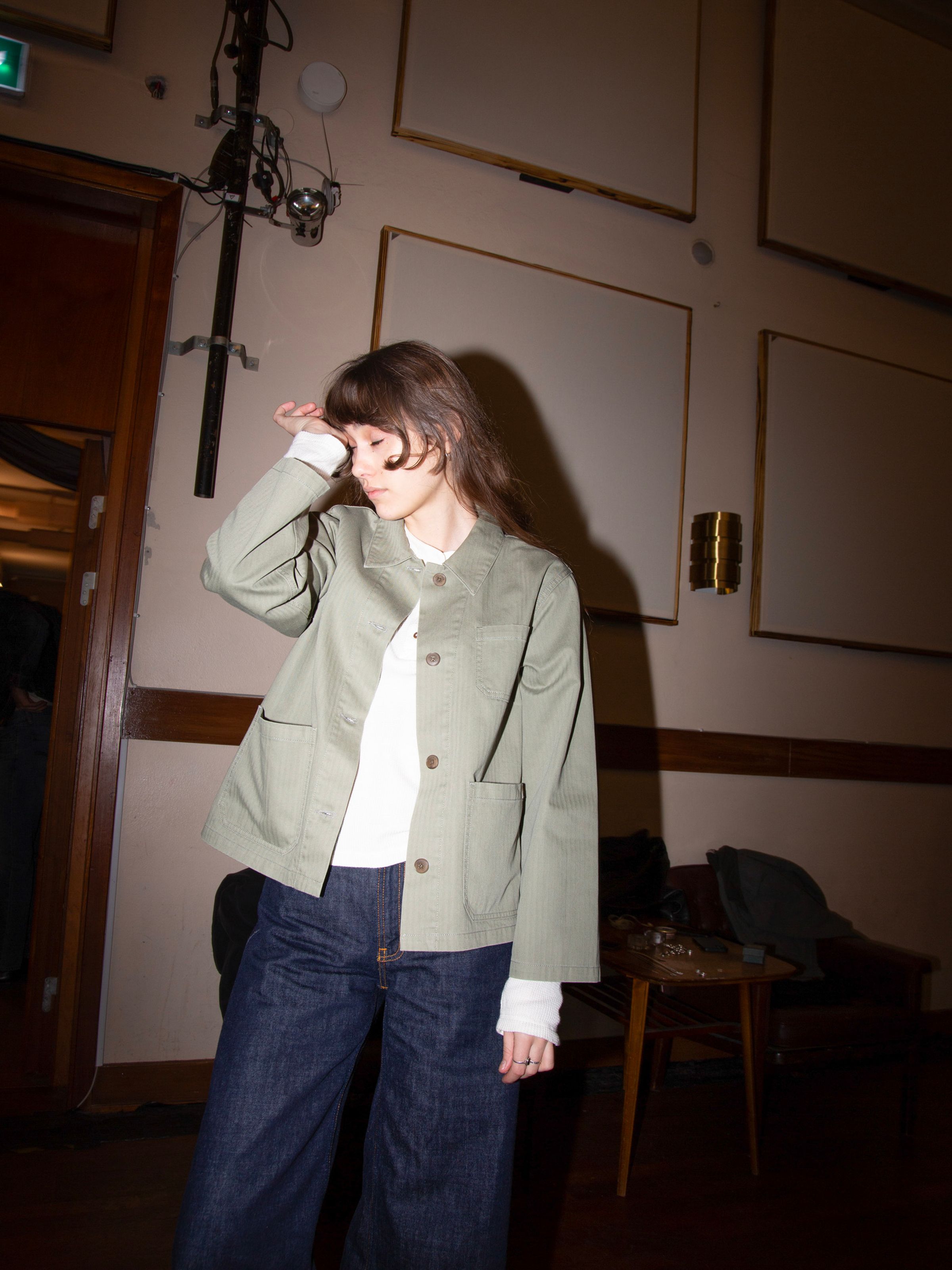 Nudie Jeans Lovis Herringbone Jacket in Pale Green, Damenjacke, von einem Model in einem Innenraum getragen.