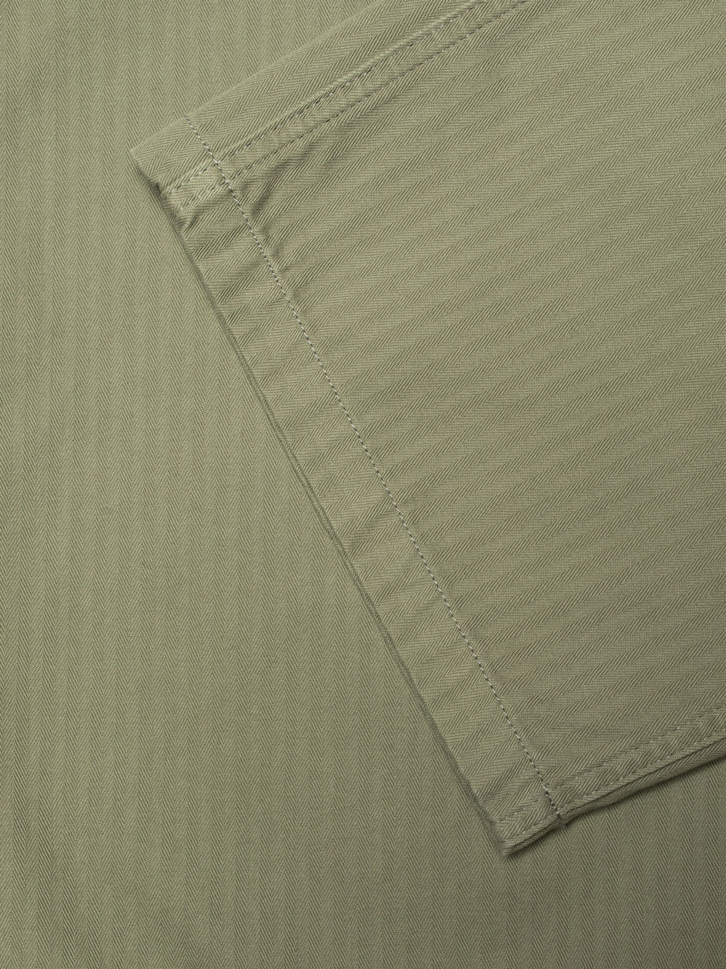 Nudie Jeans Wendy Herringbone Pale Green, women's wide-leg pants, close-up of the pale green herringbone twill fabric.