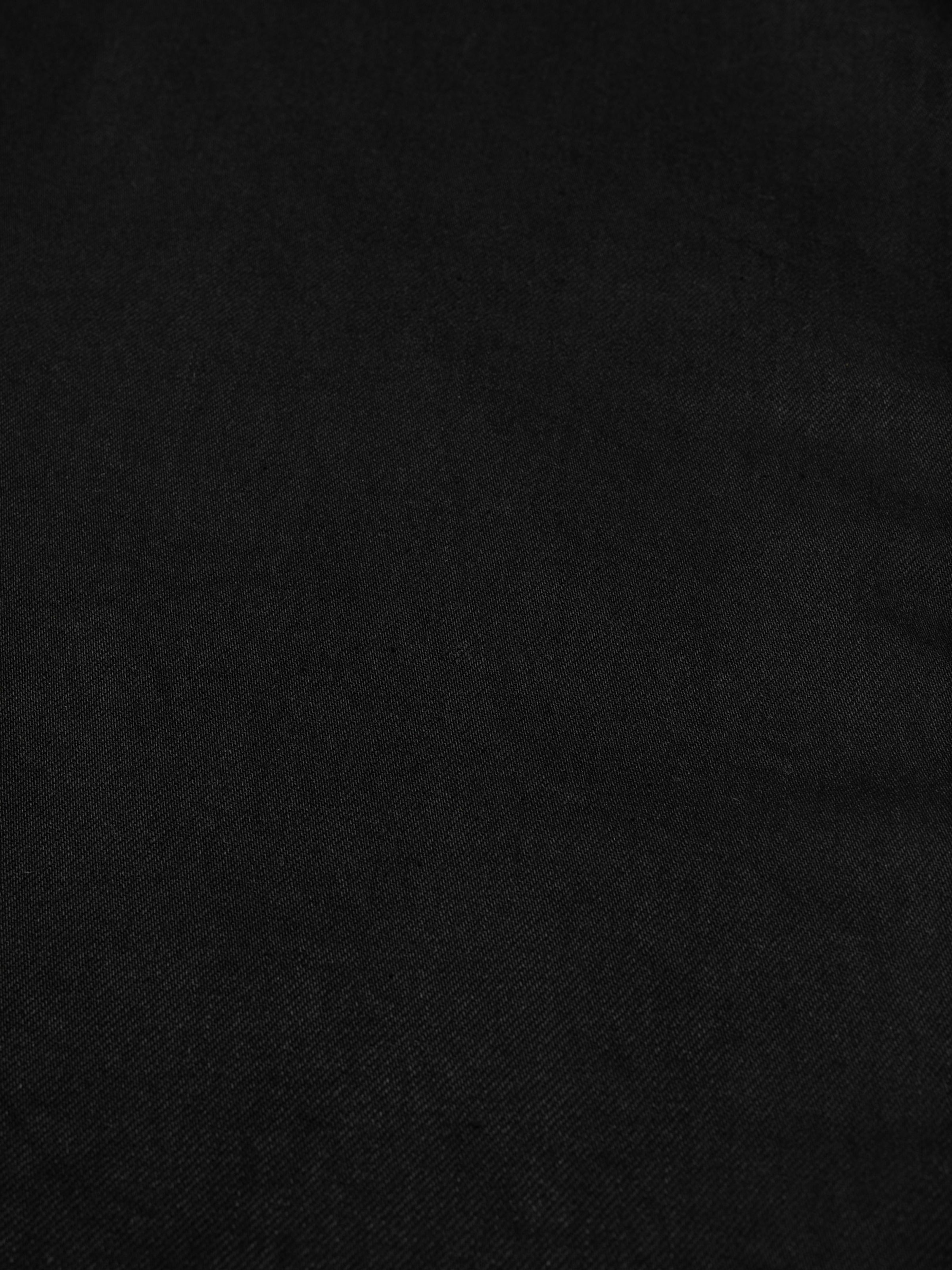 Nudie Jeans Loud Larry Black Water, a pair of men's loose fit jeans in black denim, shown in a close-up of the fabric.
