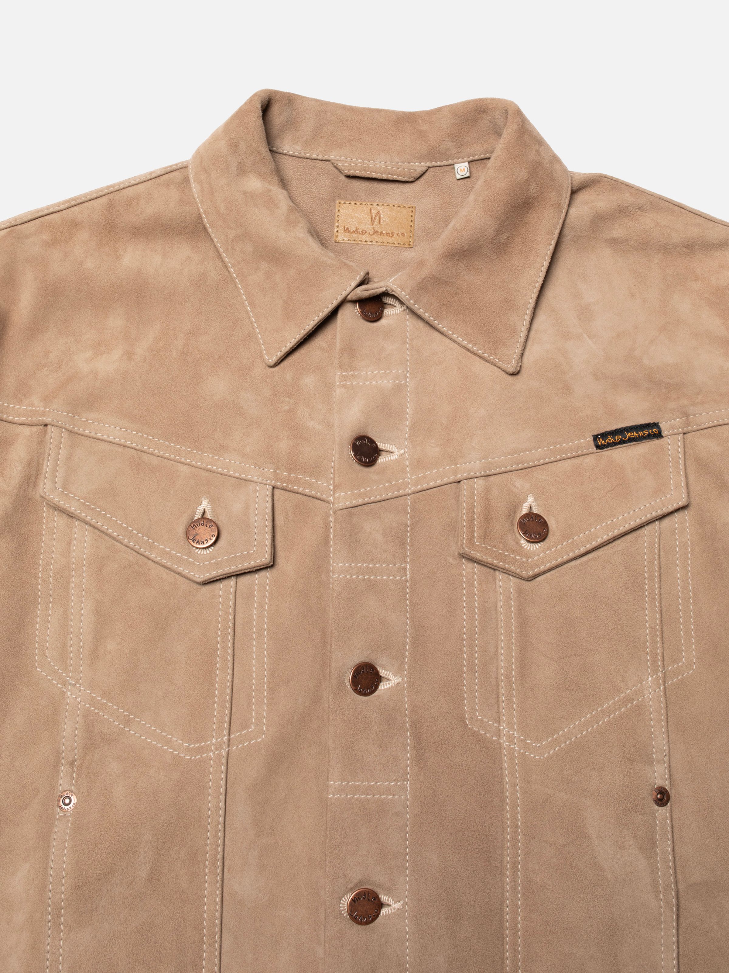 Nudie Jeans Willy Suede Jacket Mud, close-up of the front showing the collar, copper logo buttons, and chest pockets.