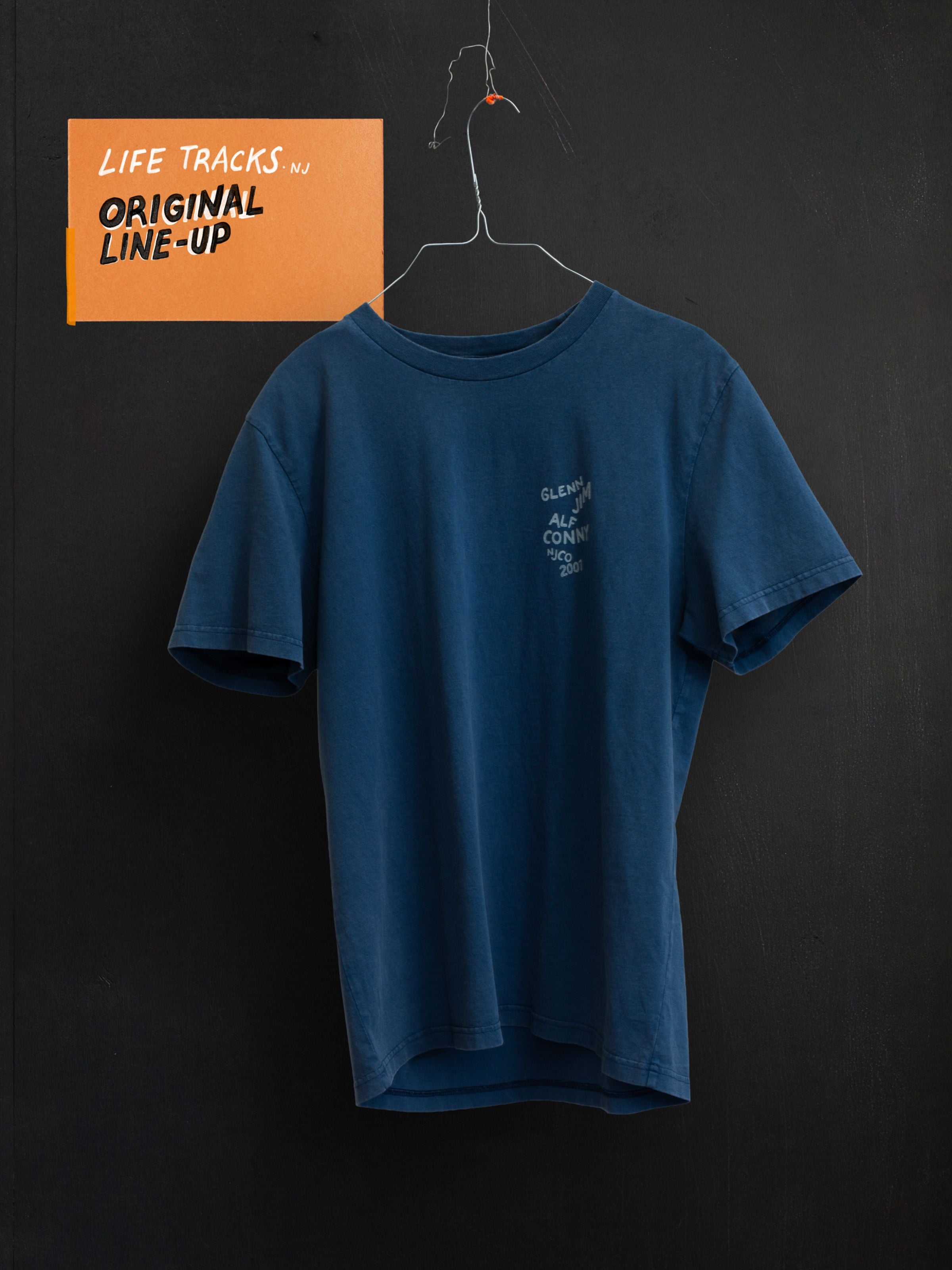 Roy T-Shirt OG Line-Up in French Blue, a relaxed-fit organic cotton t-shirt with chest graphic hanging on a wire hanger.