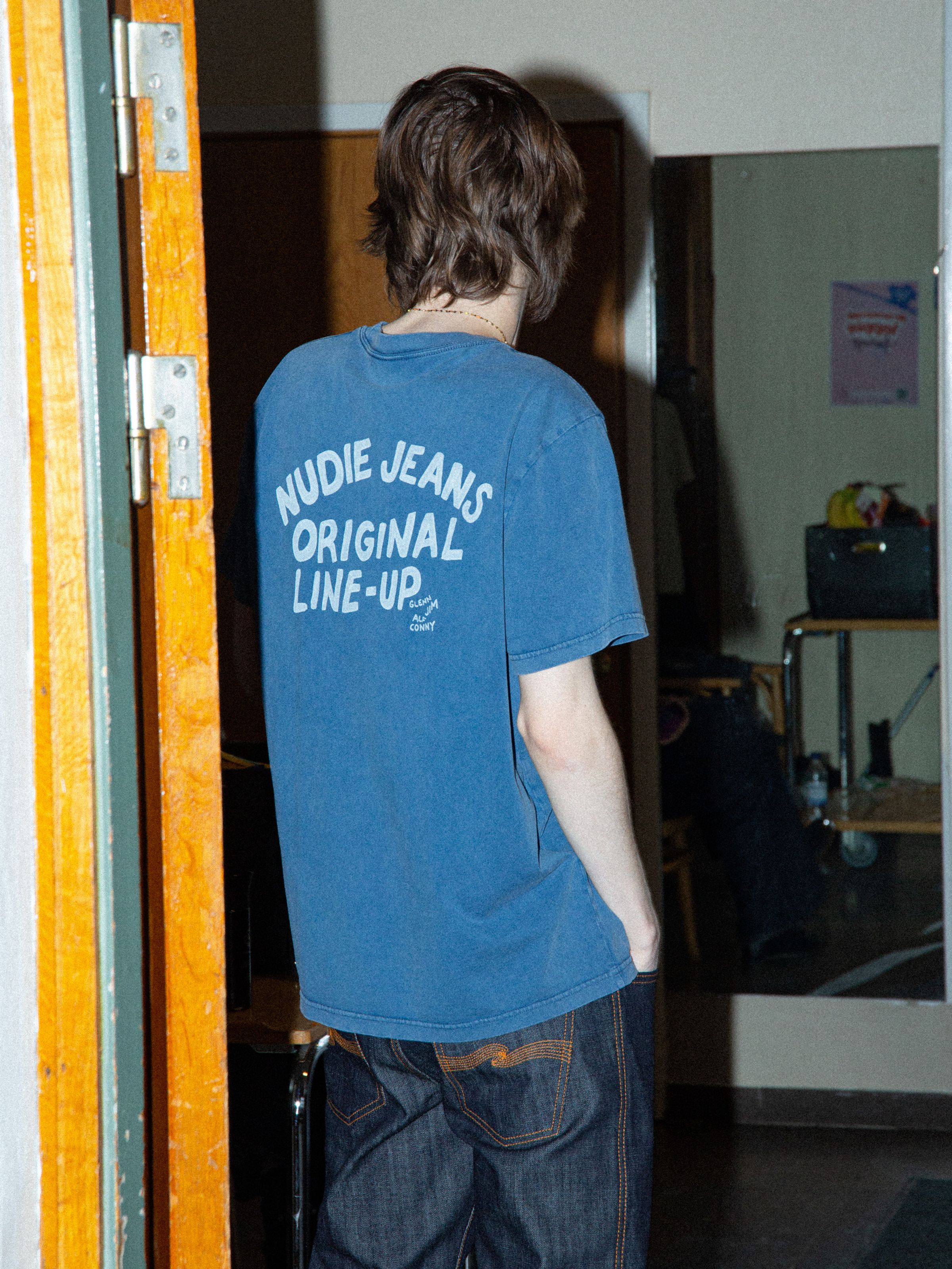 Nudie Jeans Roy T-Shirt OG Line-Up in French Blue, showing the back graphic print on a model.