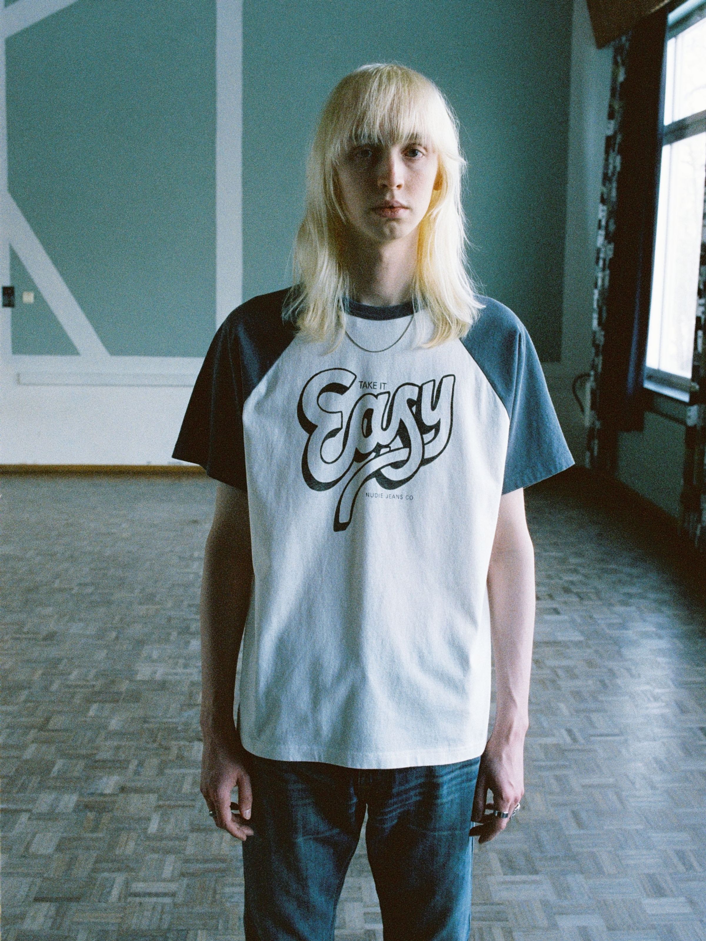 Nudie Jeans Roy Raglan T-Shirt Take It Easy, Herren-T-Shirt aus Bio-Baumwolle, von vorne an einem Model gezeigt.