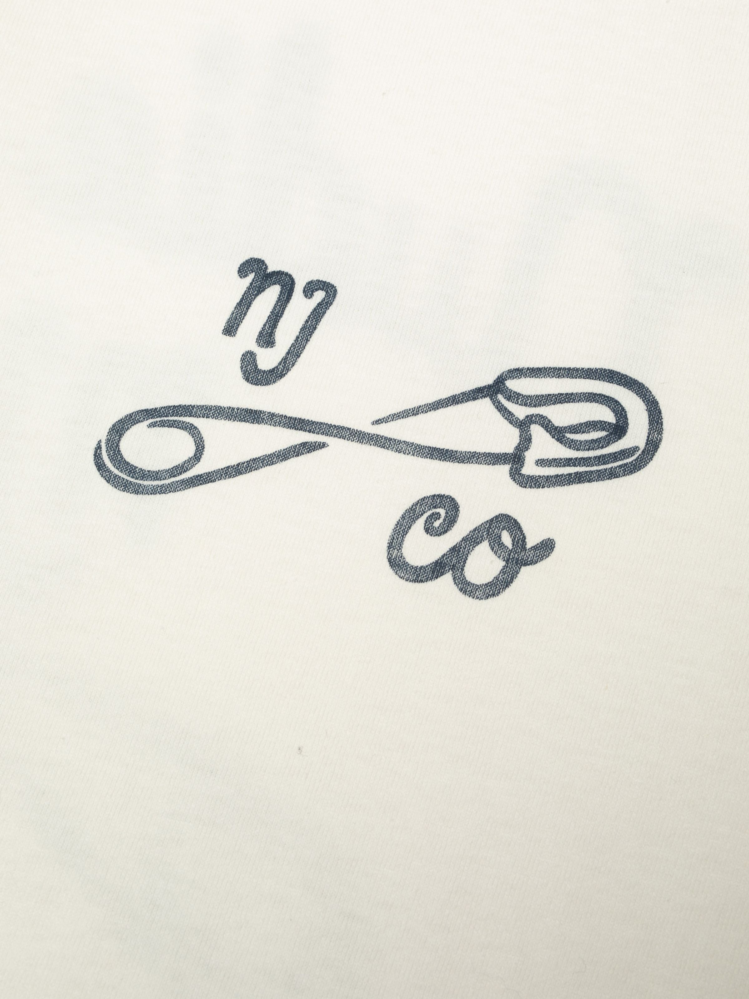 Nudie Jeans Roy T-Shirt NJCO Pin in Chalk White, close-up of the safety pin graphic on the chest.