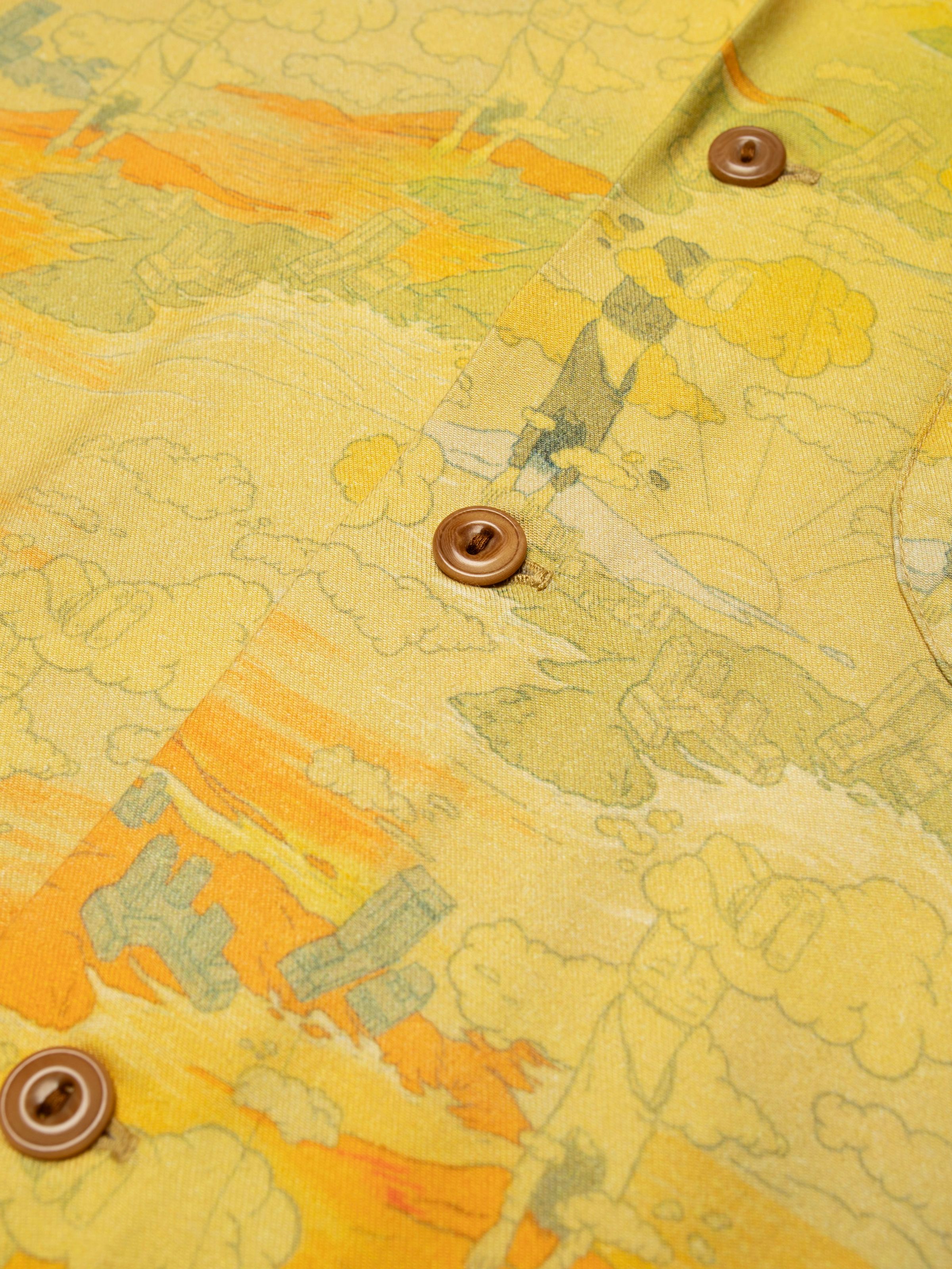 Nudie Jeans Arvid Hawaii Shirt Drift Away, close-up of the surrealist yellow pattern and brown Corozo buttons.