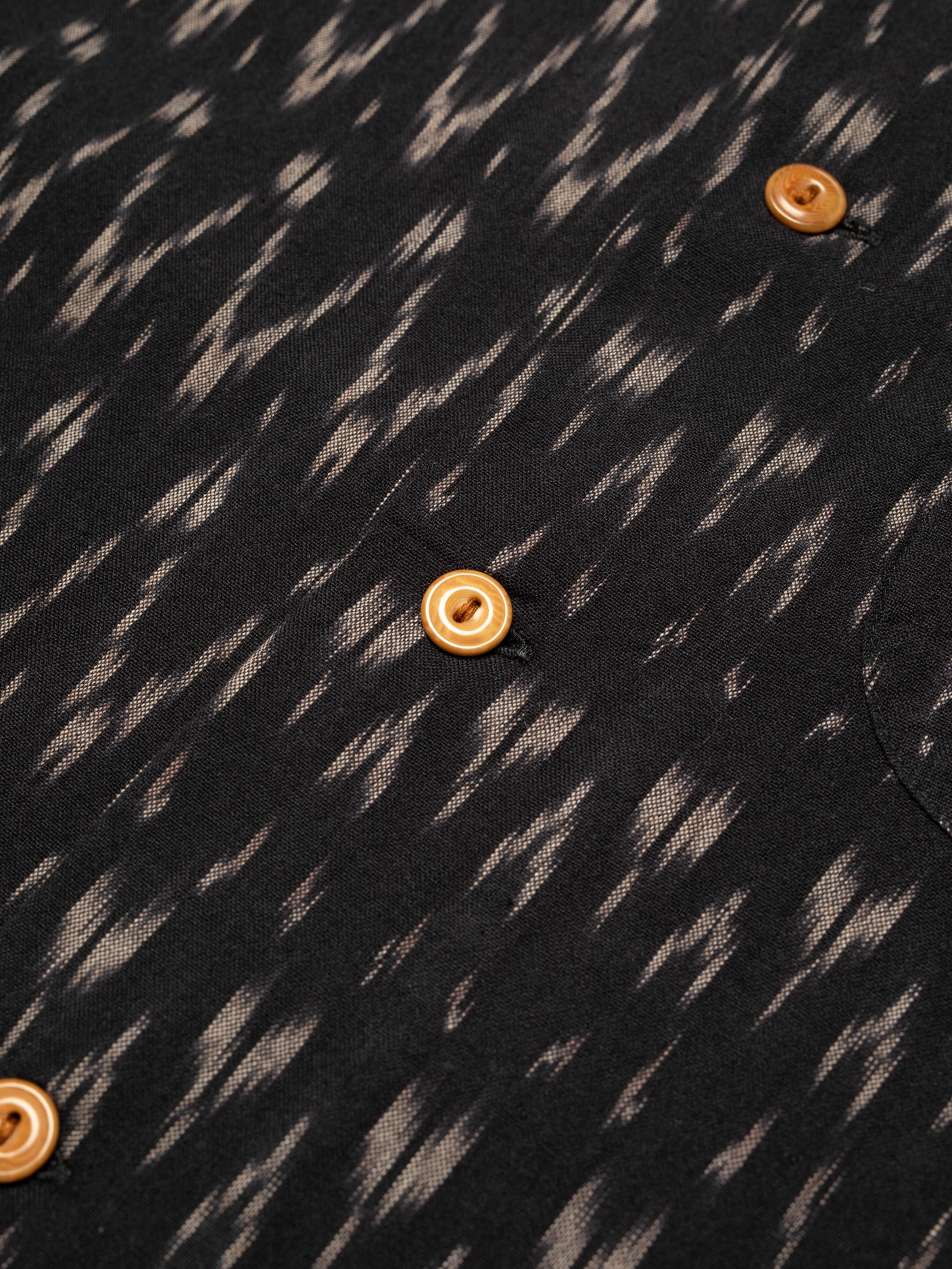 Nudie Jeans Arvid Hawaii Shirt Ikat, close-up of the black ikat pattern and corozo buttons.