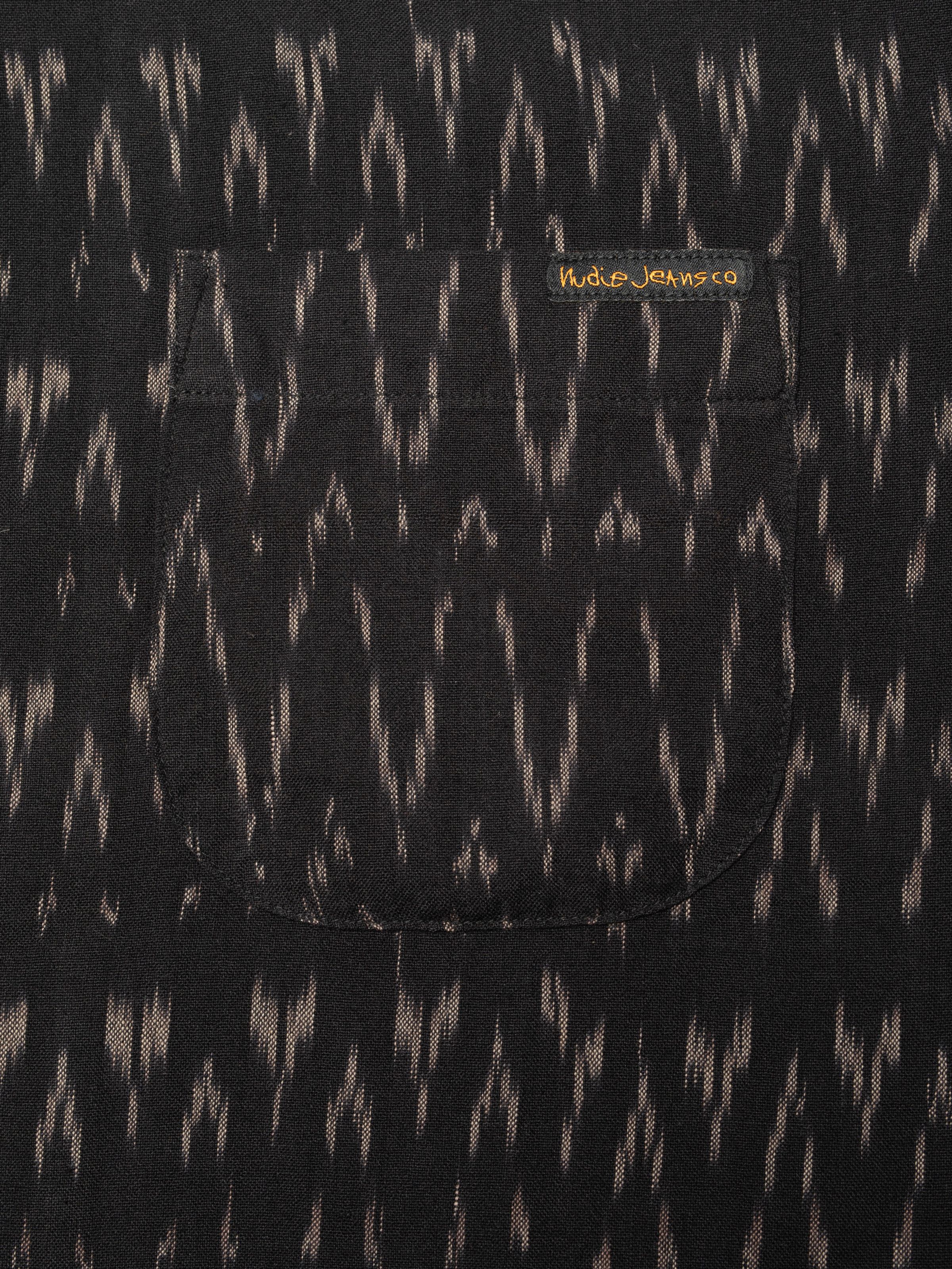 Nudie Jeans Arvid Hawaii Shirt Ikat, close-up of the chest pocket showing the unique ikat pattern and brand label.