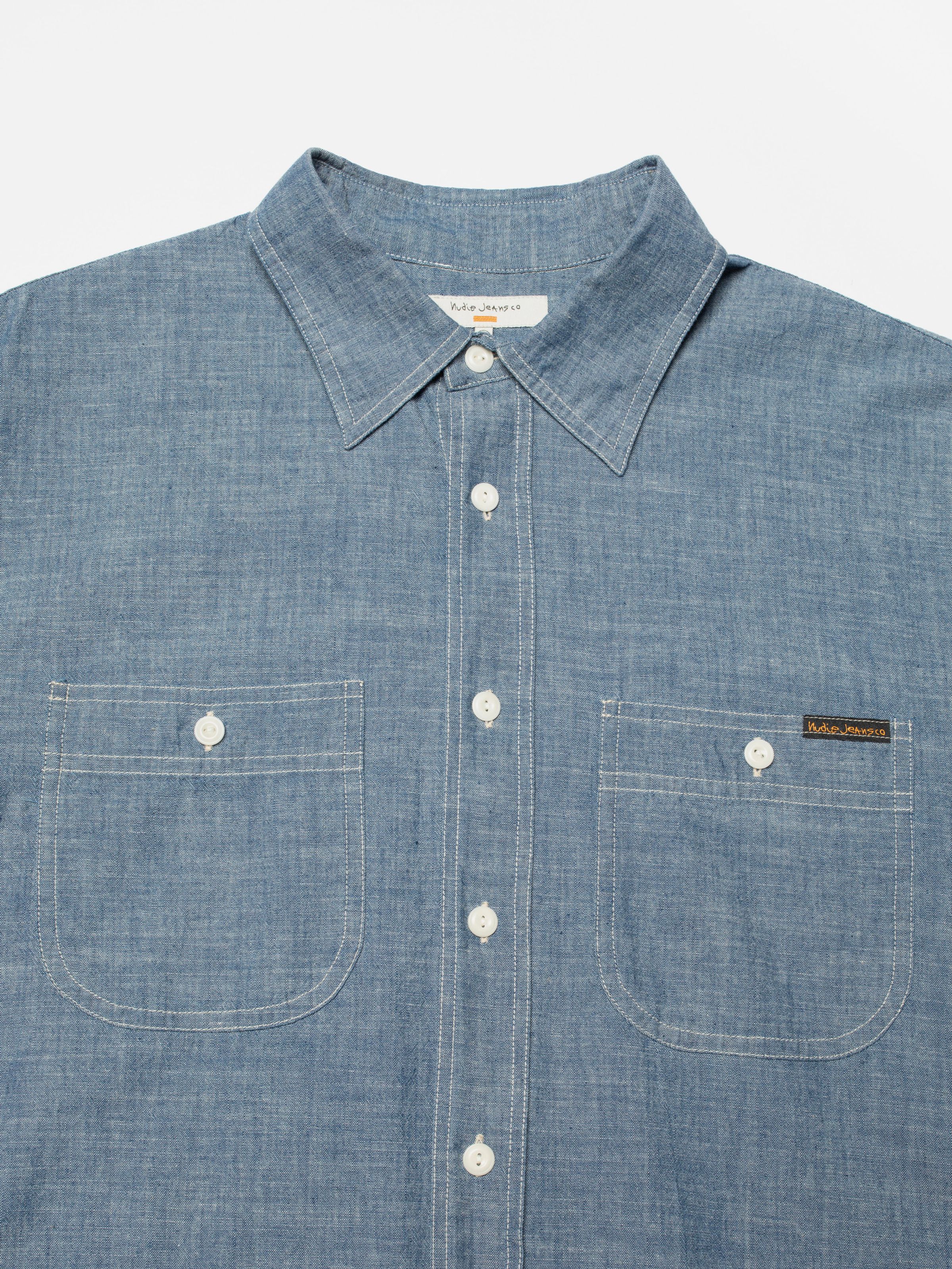 Nudie Jeans Julian Worker Shirt Chambray, close-up of the front showing the collar, buttons, and two chest pockets.