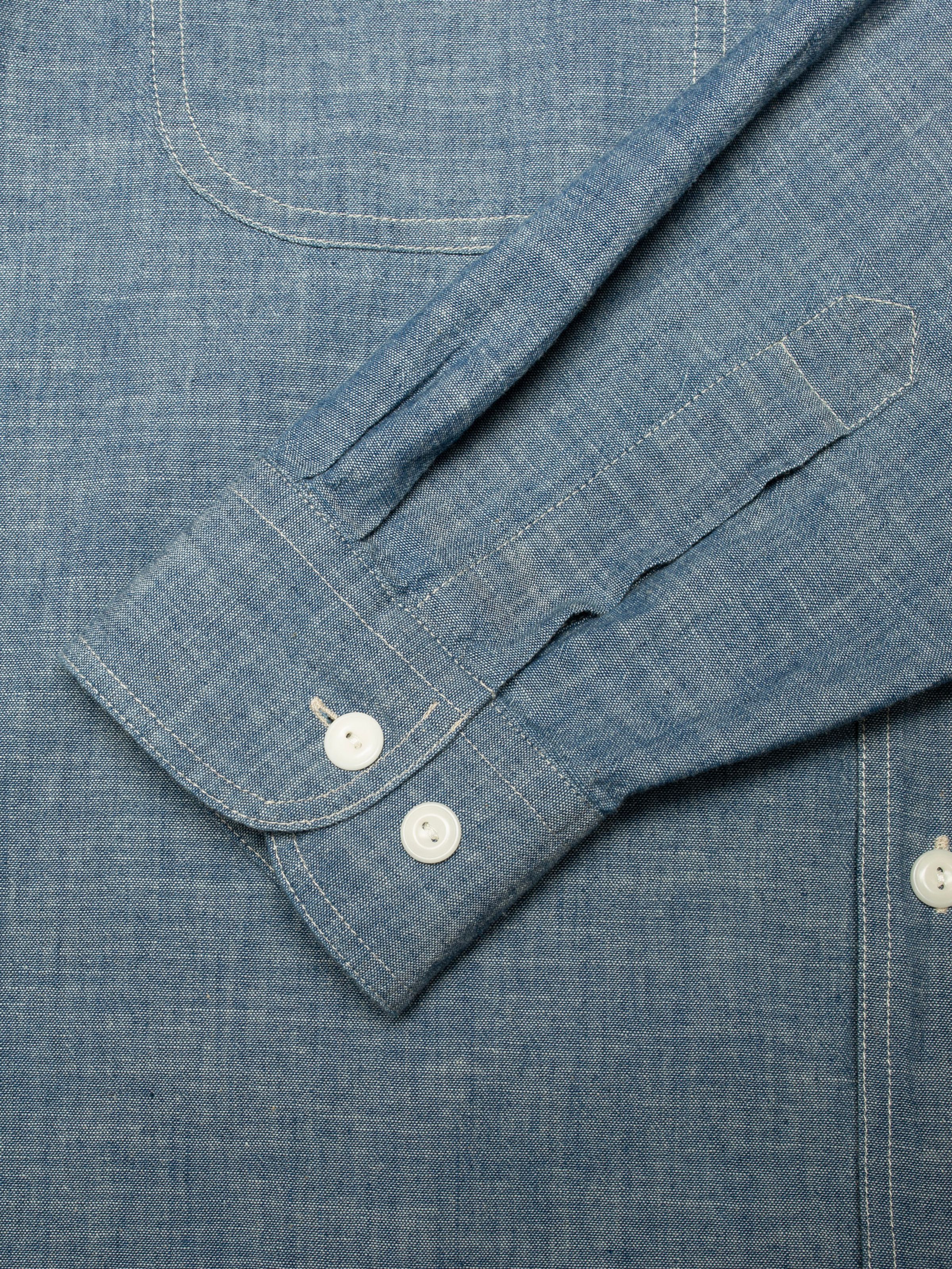 Nudie Jeans Julian Worker Shirt Chambray, close-up of the sleeve cuff with white corozo buttons and contrast stitching.