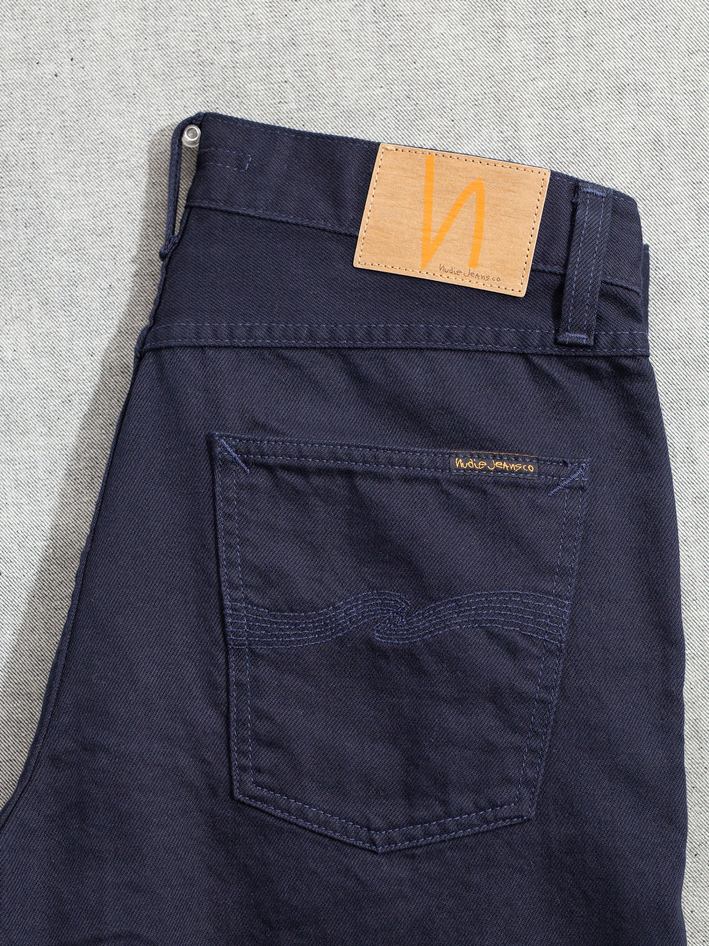 Nudie Jeans Tuff Tony Everblue, close-up of the back pocket and Jacron patch on solid dark blue rigid denim.