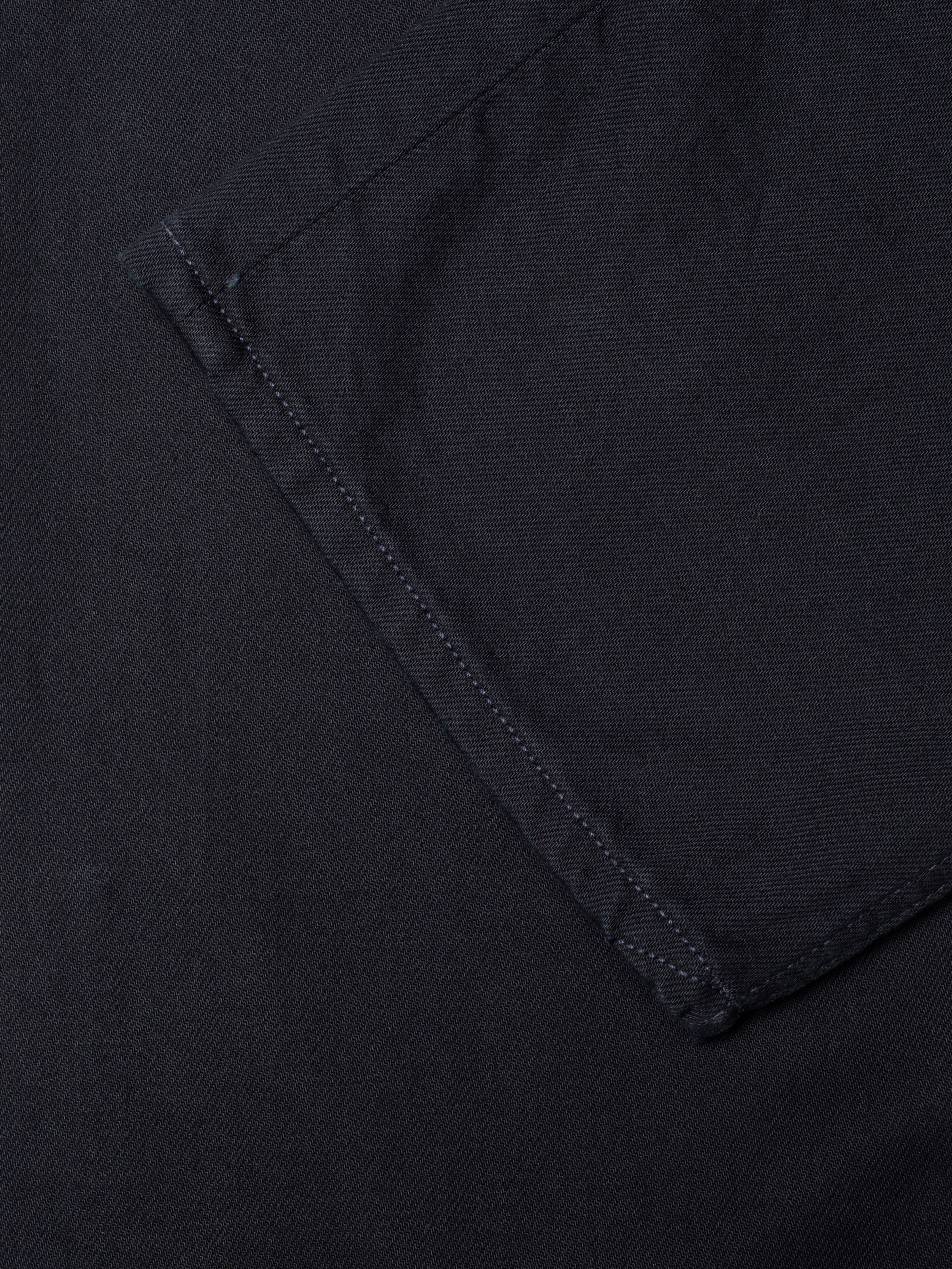 Nudie Jeans Tuff Tony Everblue, close-up of the dark blue rigid denim fabric and tonal navy thread at the seams.