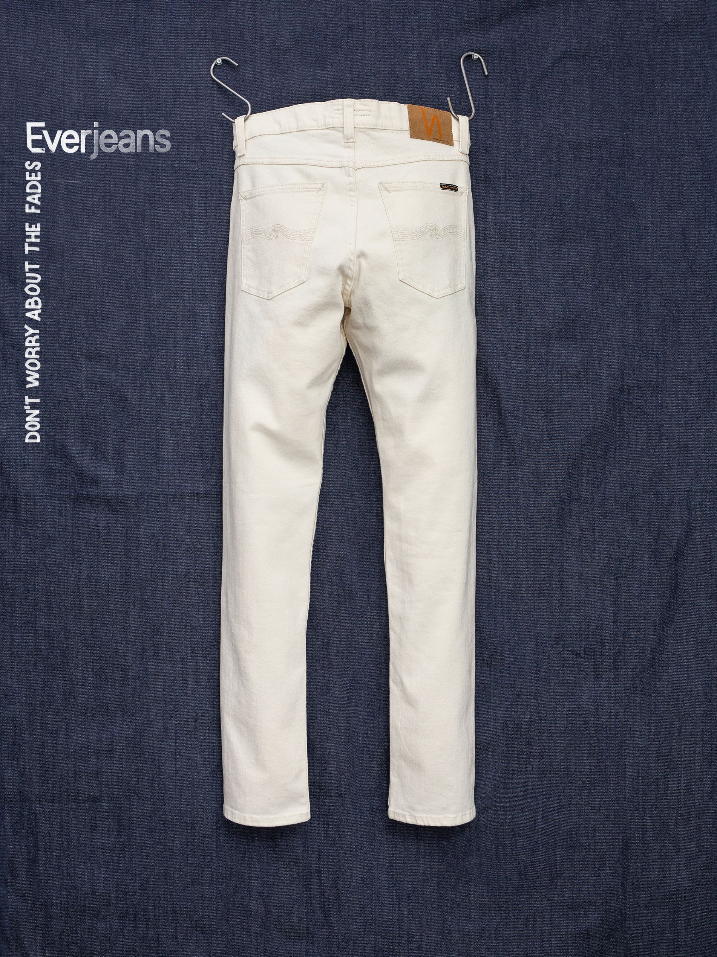 Nudie Jeans Solid Ollie Everivory, Jeans mit schmaler Passform aus Ivory-Stretchdenim, von hinten vor dunklem Denim.