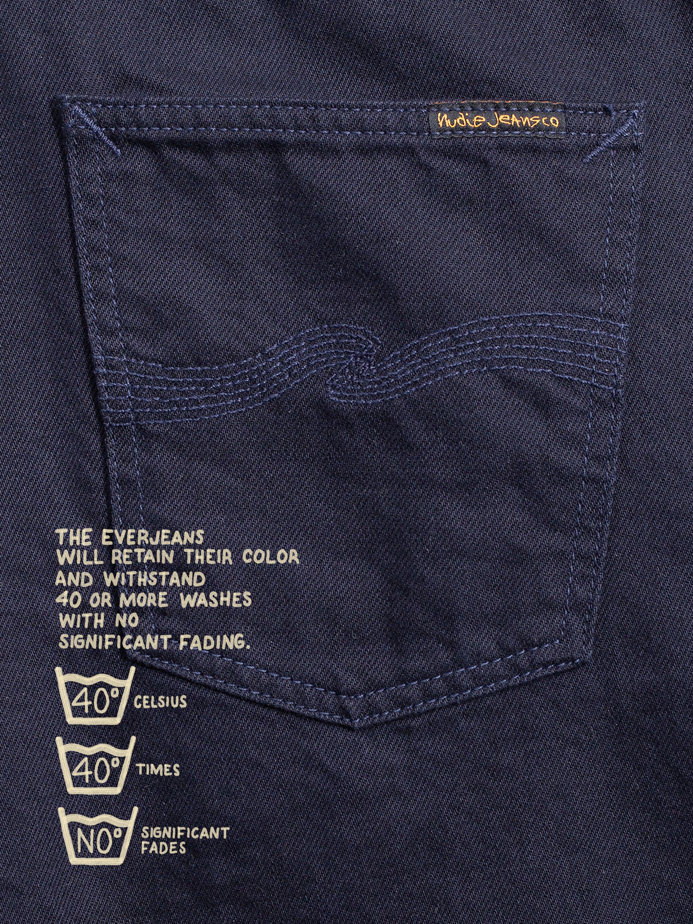 Nudie Jeans Seth Shorts Everblue, close-up of the dark blue rigid denim back pocket with tonal embroidery and printed text.