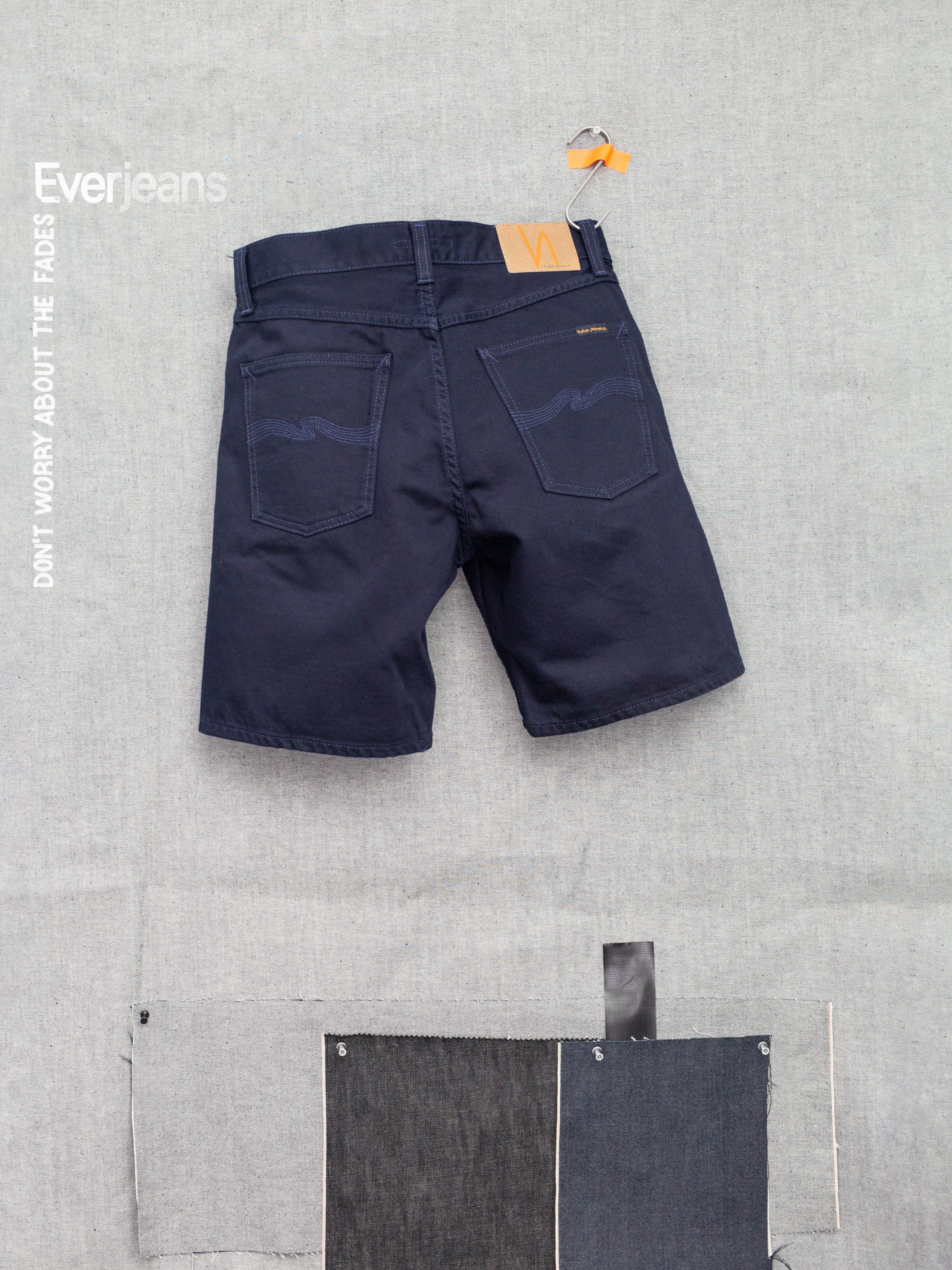 Nudie Jeans Seth Shorts Everblue, wide-leg organic rigid denim shorts in solid dark blue shown flat from the back.
