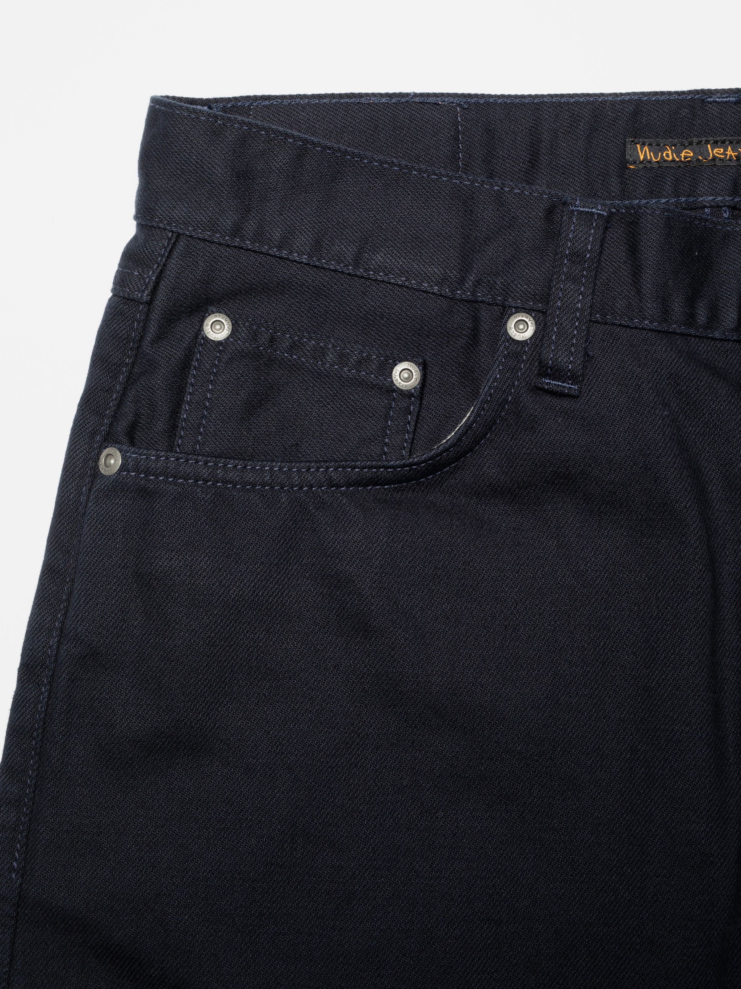 Nudie Jeans Seth Shorts Everblue, close-up showing the front pocket, antique silver rivets, and navy thread at the seams.