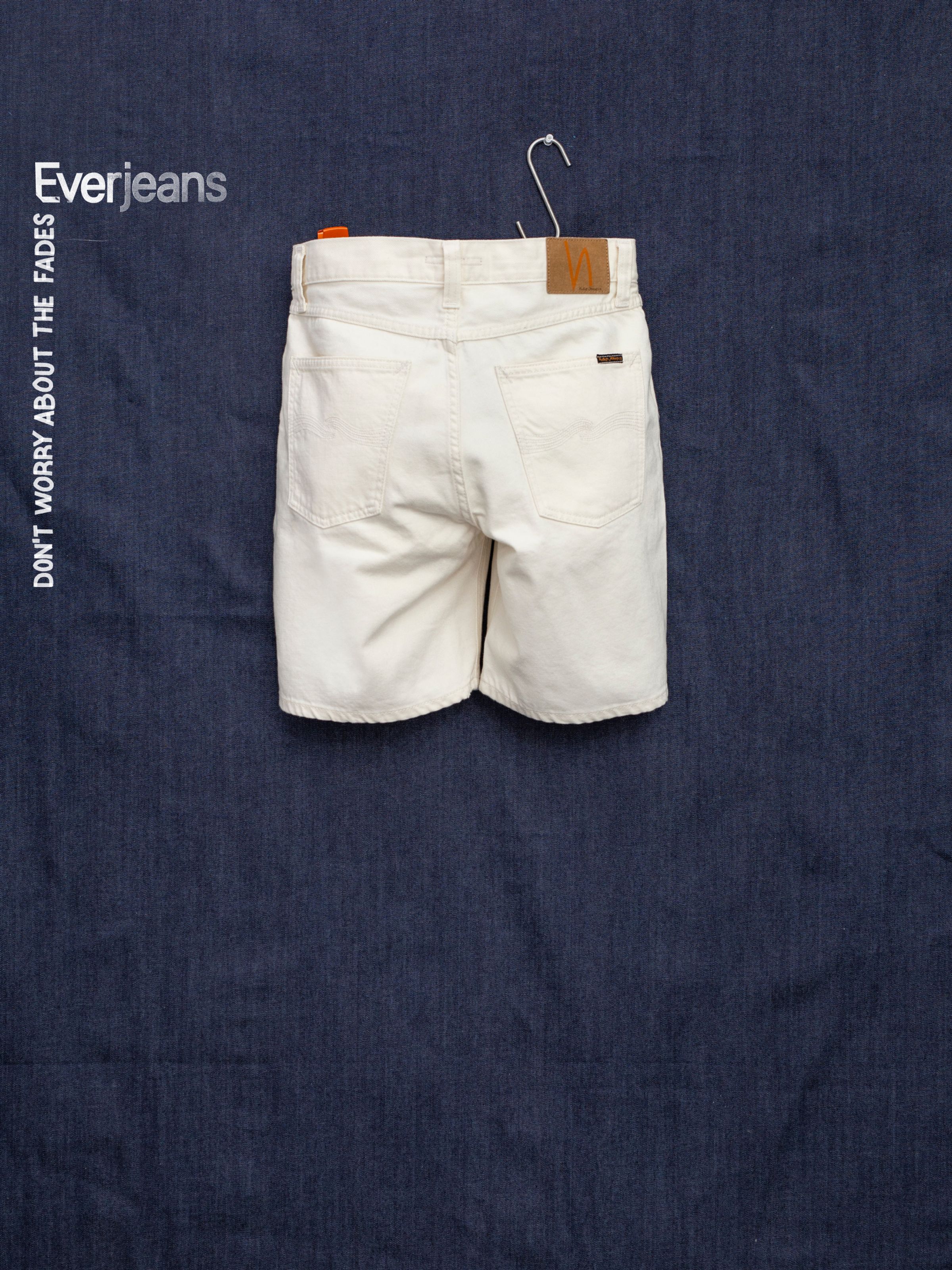 Nudie Jeans Seth Shorts Everivory, wide-leg organic denim shorts in ivory, shown from the back against dark blue denim.