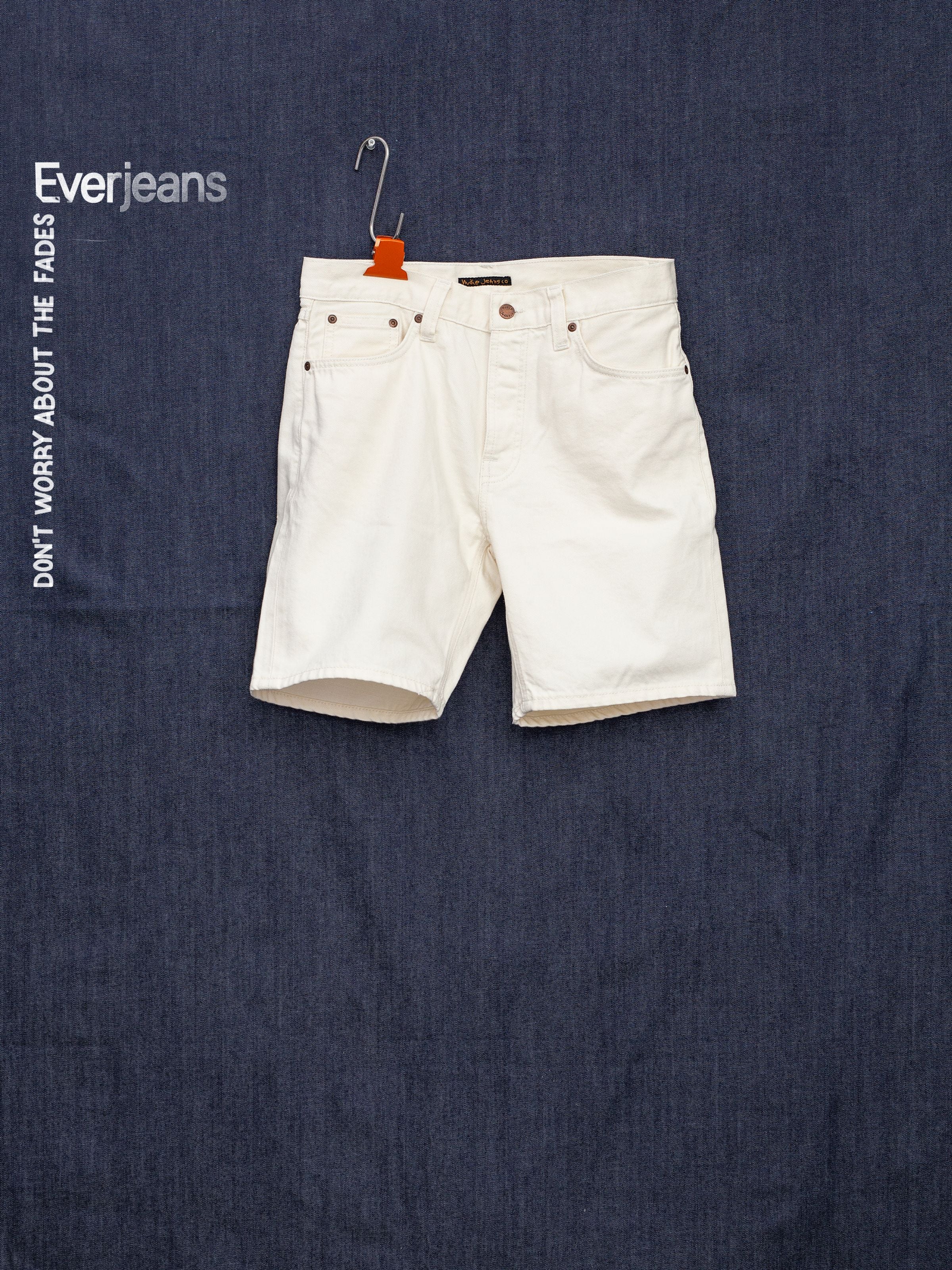 Nudie Jeans Seth Shorts Everivory, rigid organic ivory denim wide-leg shorts in a front flat lay against dark denim.